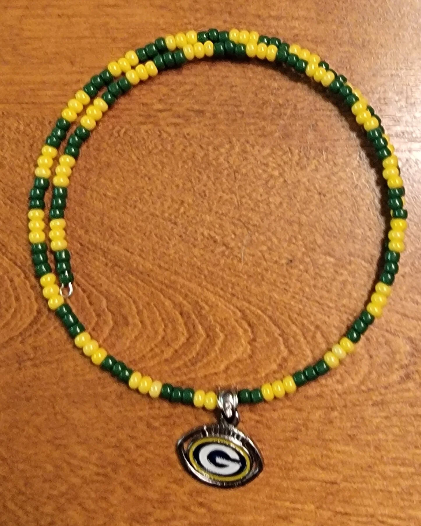 Beaded necklace with green and yellow beads and a pendant featuring the Green Bay Packers logo.