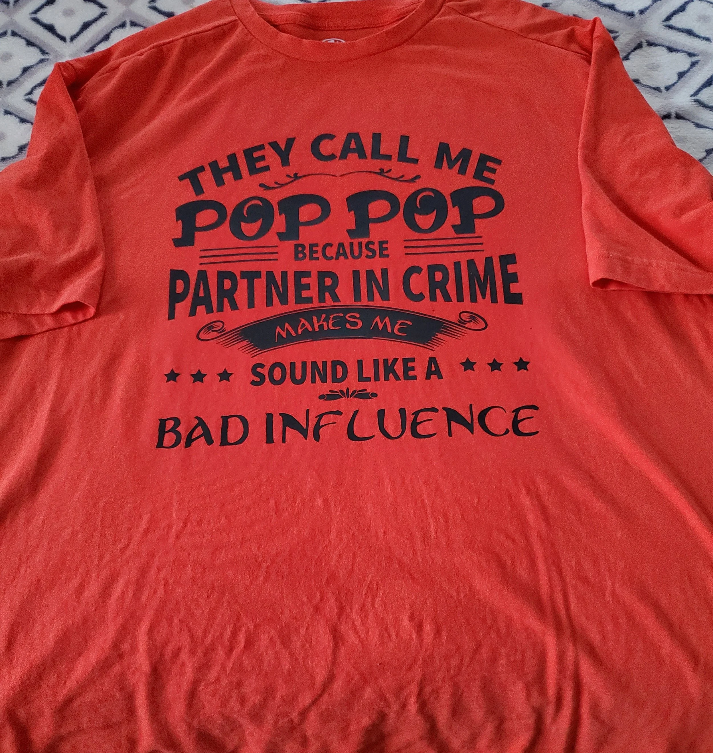 Red T-shirt with black text that reads: "They call me pop pop because partner in crime makes me sound like a bad influence."