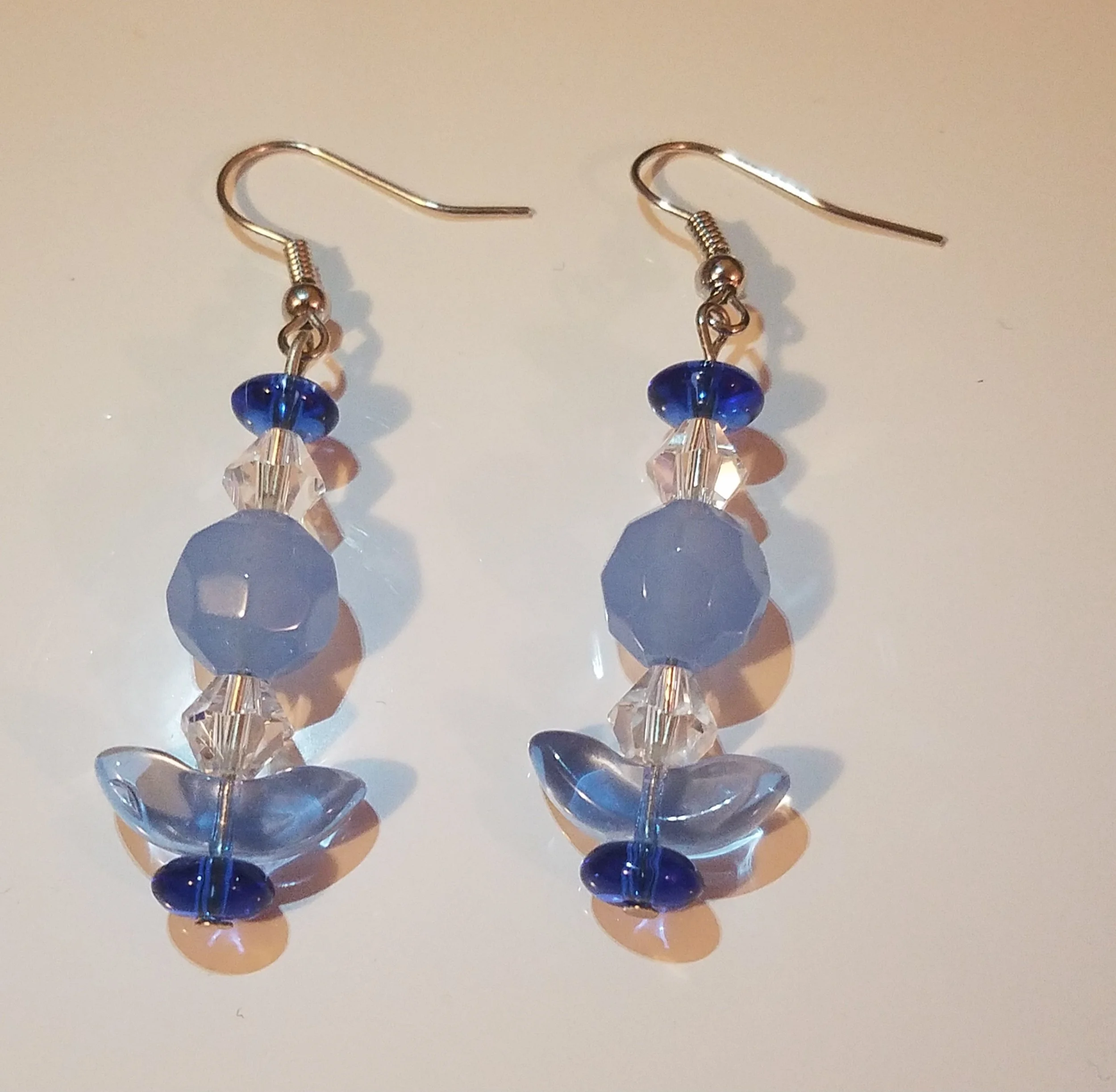 Pair of dangling earrings with blue, clear, and purple beads on a white background.
