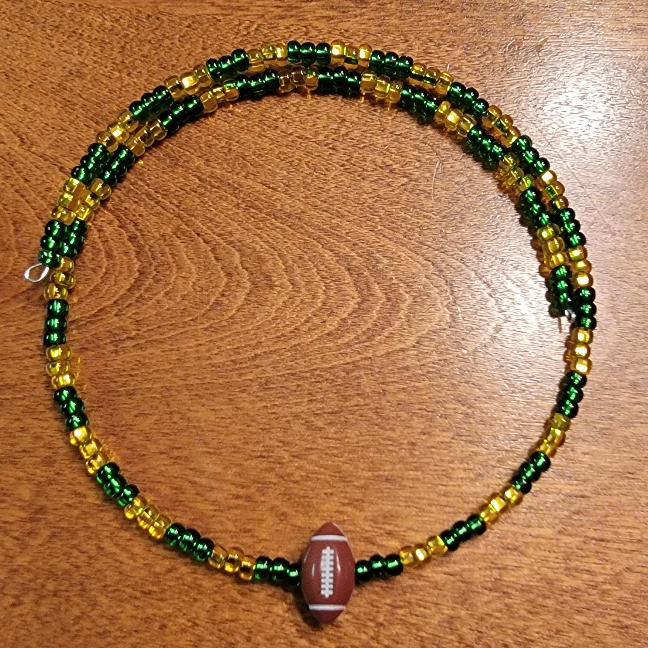 Beaded necklace with green, yellow, and black beads, and a football-shaped pendant.
