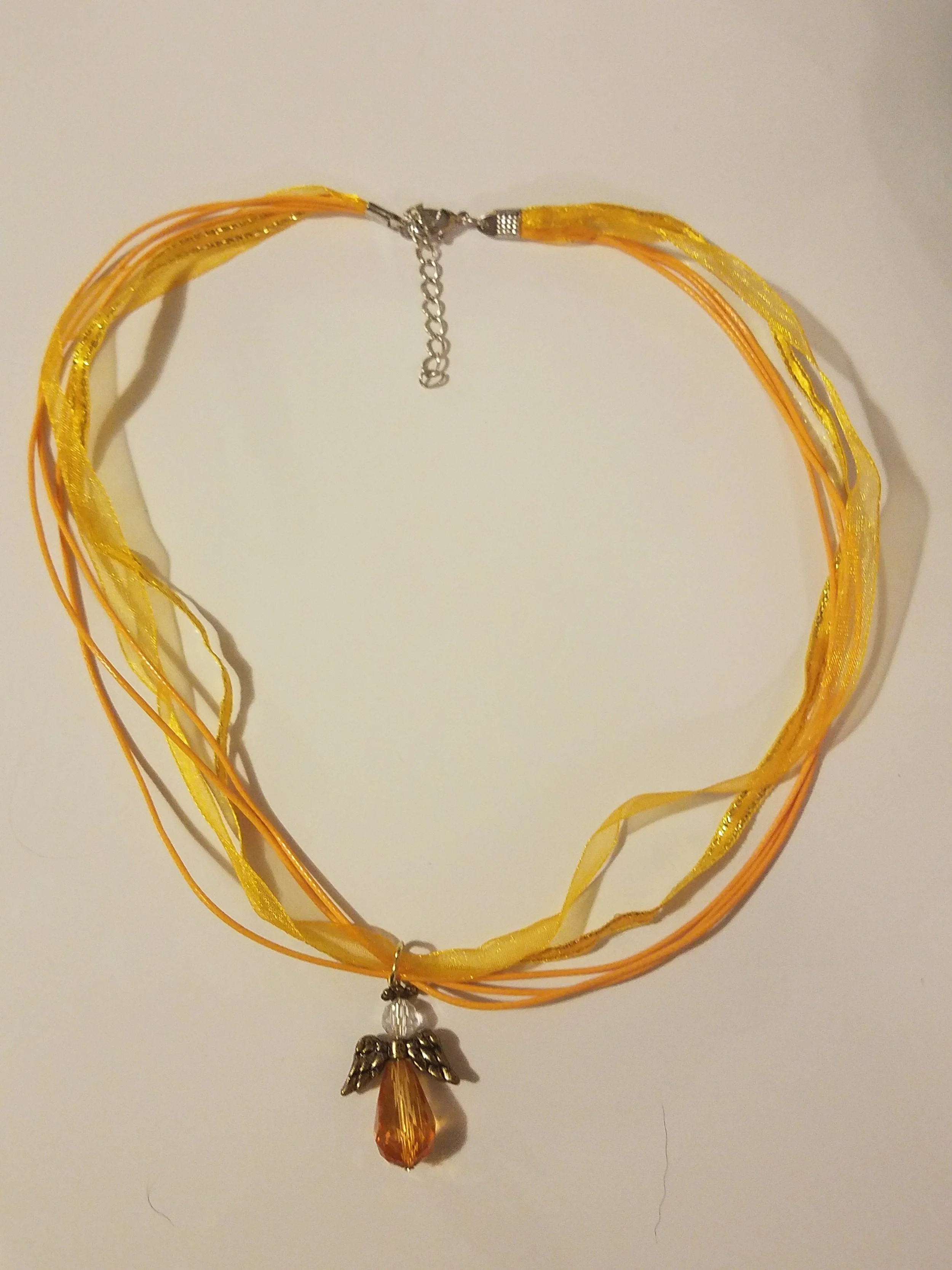 Yellow and orange ribbon choker necklace with angel and teardrop pendant.