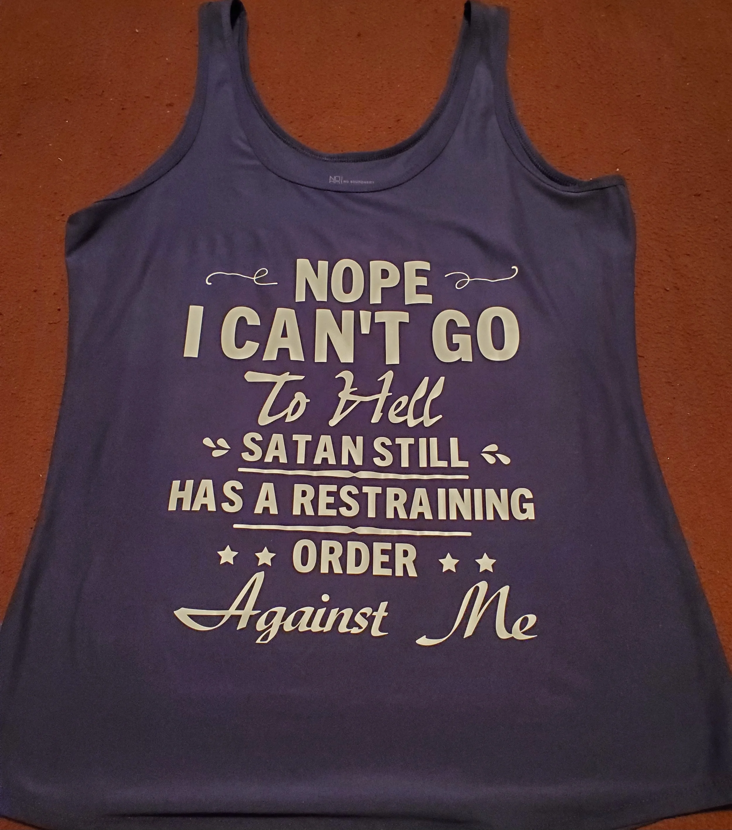 A purple sleeveless tank top with white text that reads, "NOPE I CAN'T GO To Hell SATAN STILL HAS A RESTRAINING ORDER Against Me."