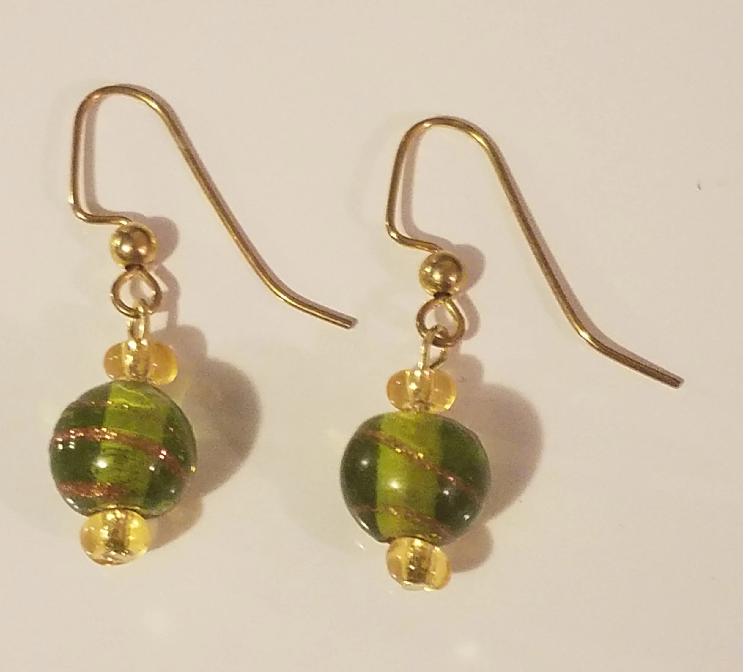 Gold hook earrings with green and gold striped beads and small yellow beads.
