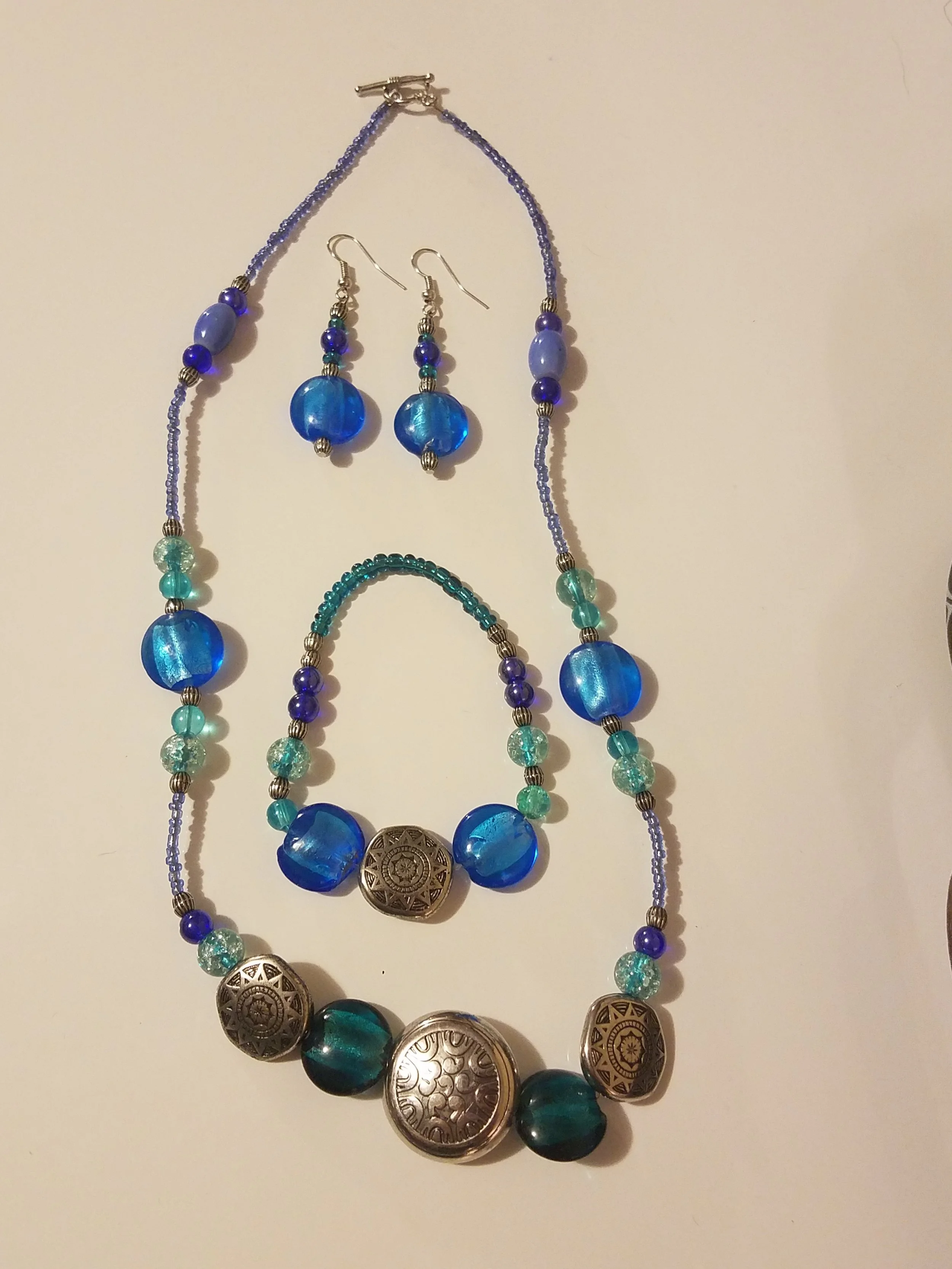 Set of blue and silver jewelry including a beaded necklace, a bracelet, and a pair of earrings with blue beads and ornate silver accents.