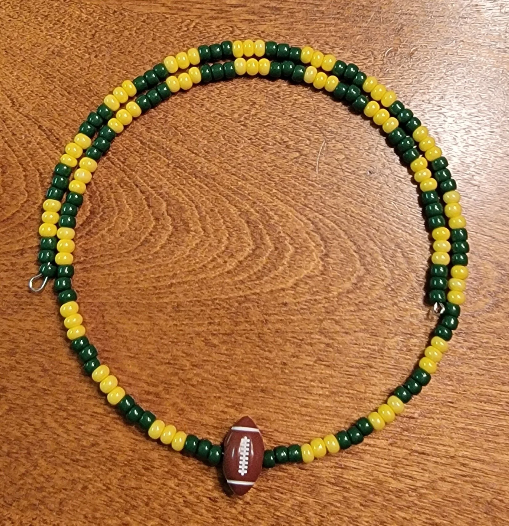 Beaded necklace with green and yellow beads and a football-shaped pendant.