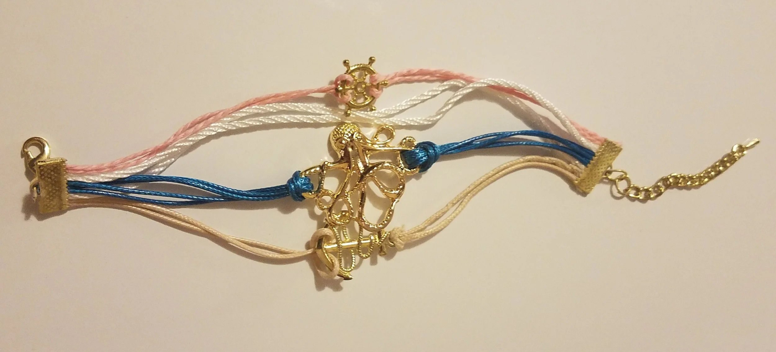 Multiple colorful strings with gold charms and clasps arranged on a white surface.