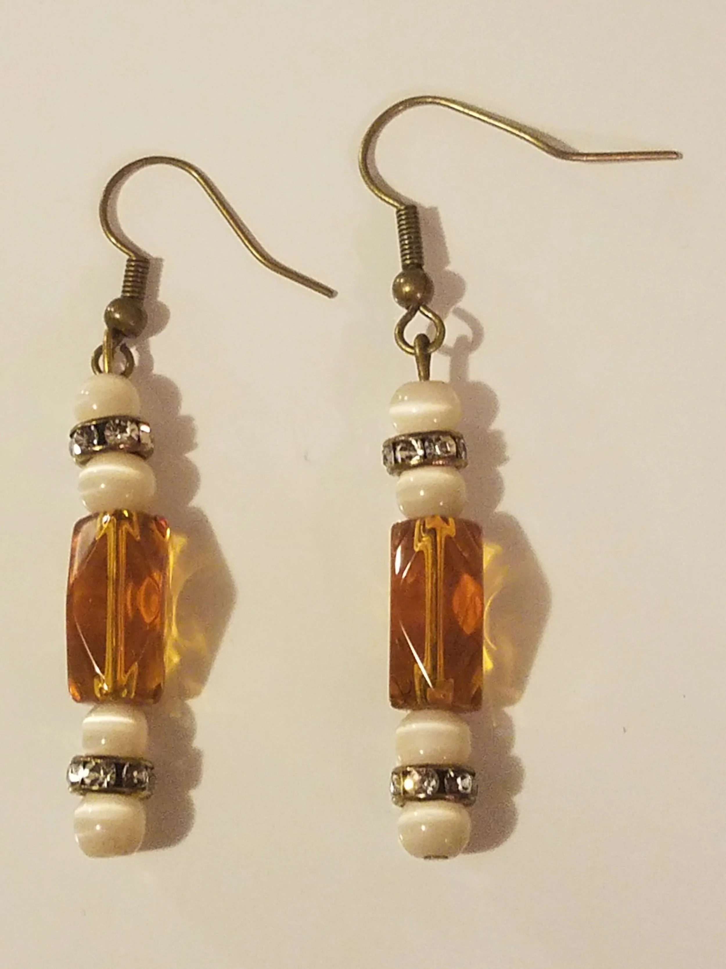 Beaded dangle earrings with orange, white, and rhinestone beads.