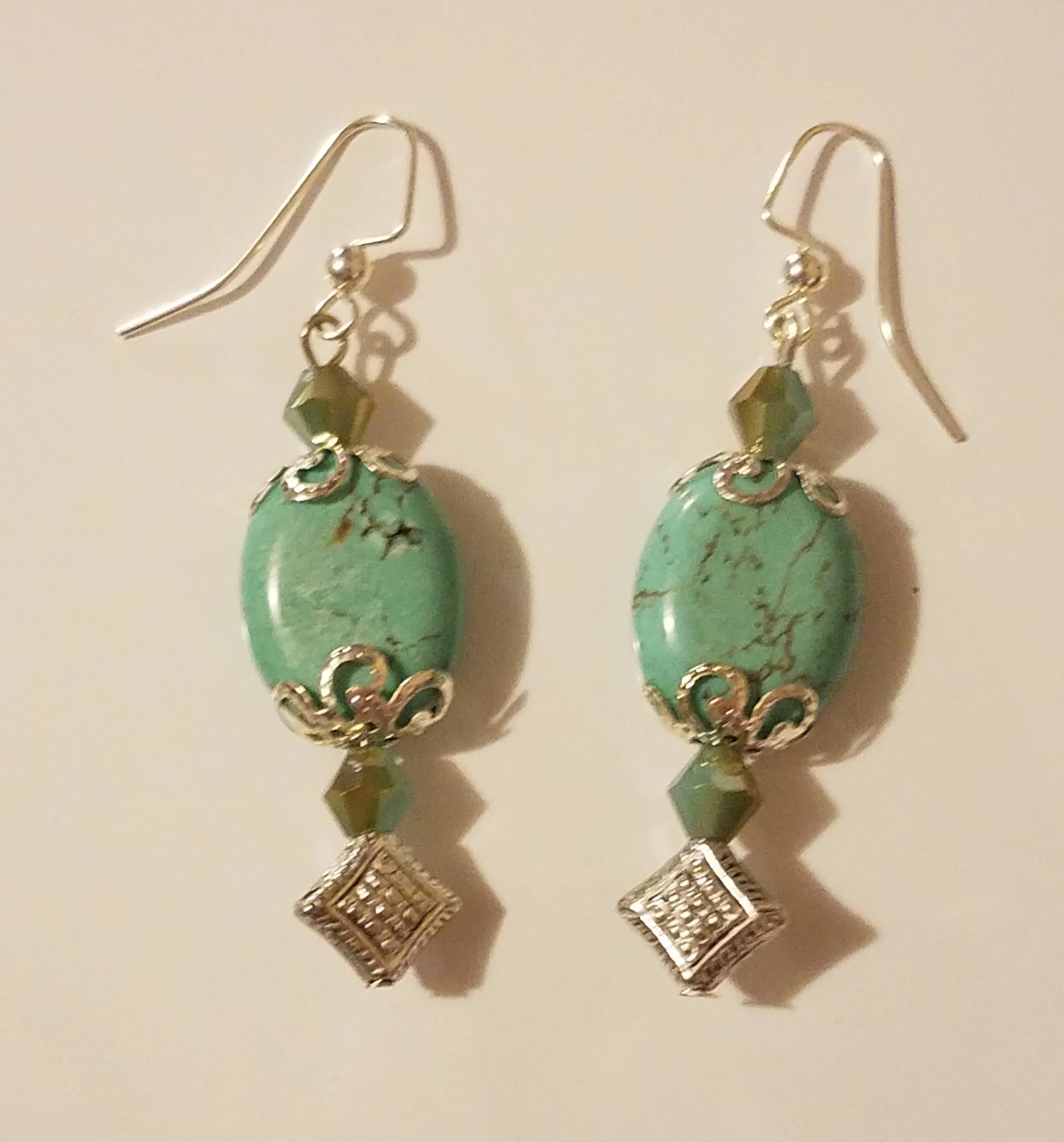 Drop earrings with green oval stones, small green faceted beads, and silver decorative elements.