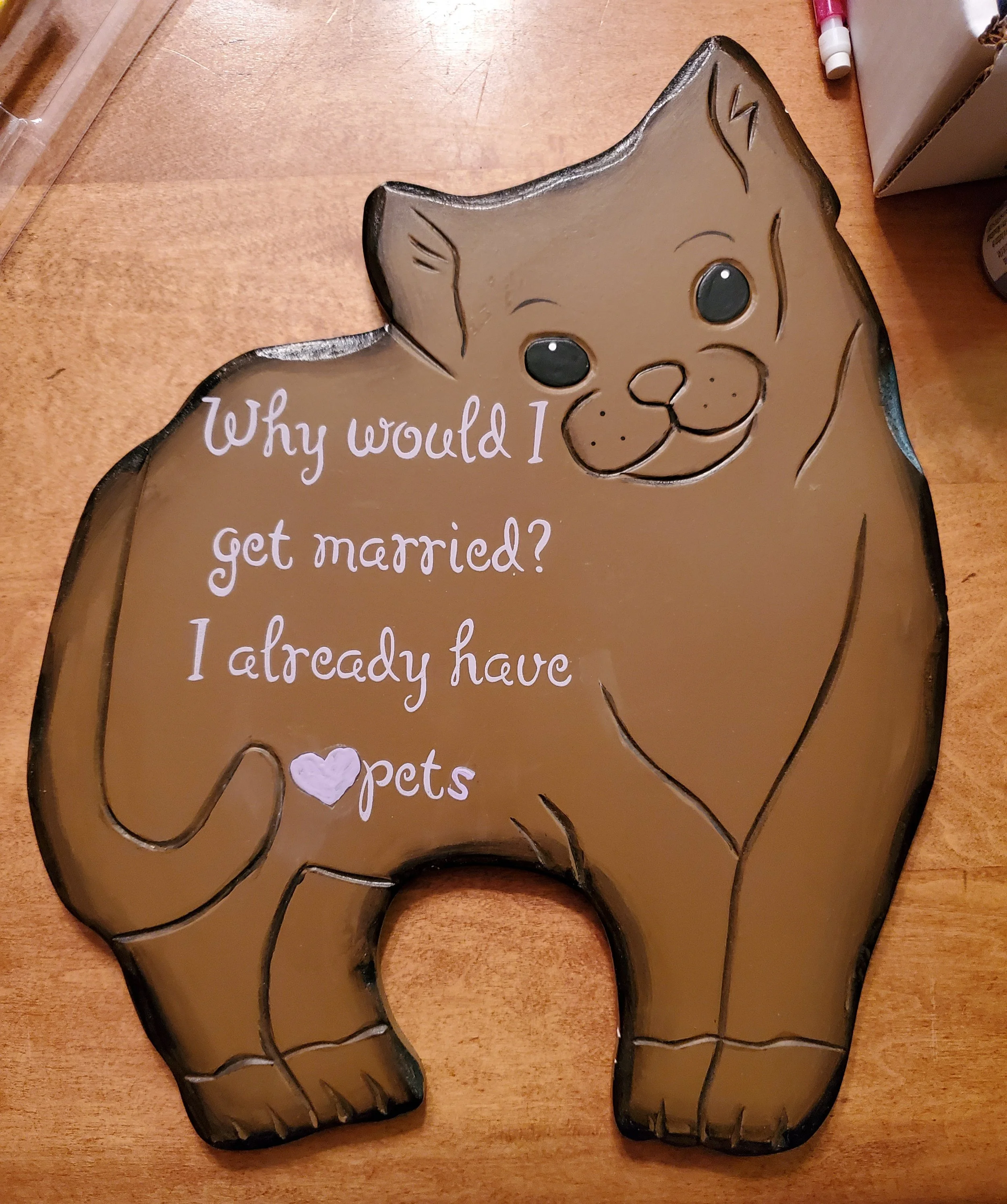 Decorative sign in the shape of a cat with a humorous message about pets.