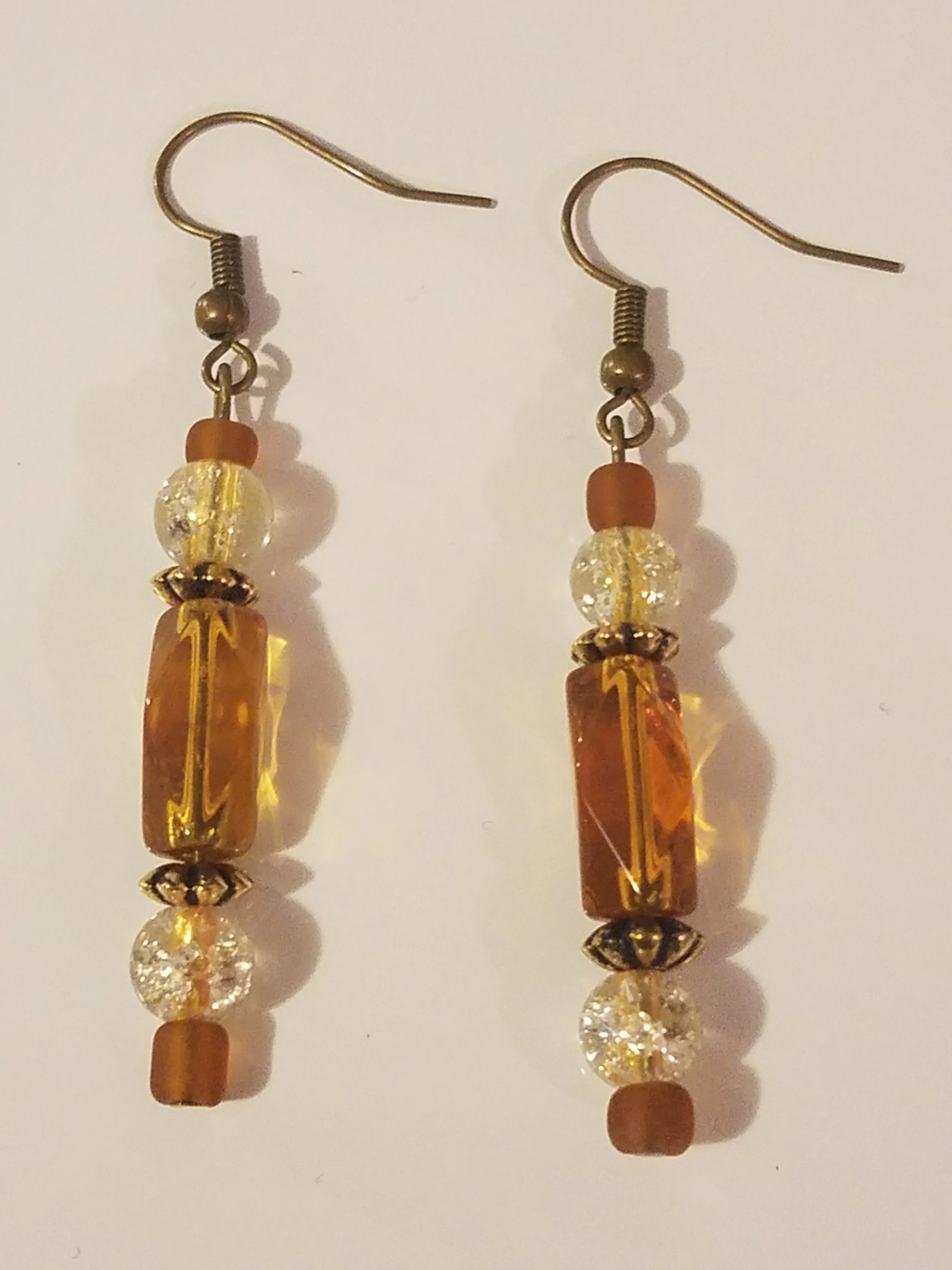 Beaded earrings with amber, clear, and bronze beads, hanging from metal hooks.