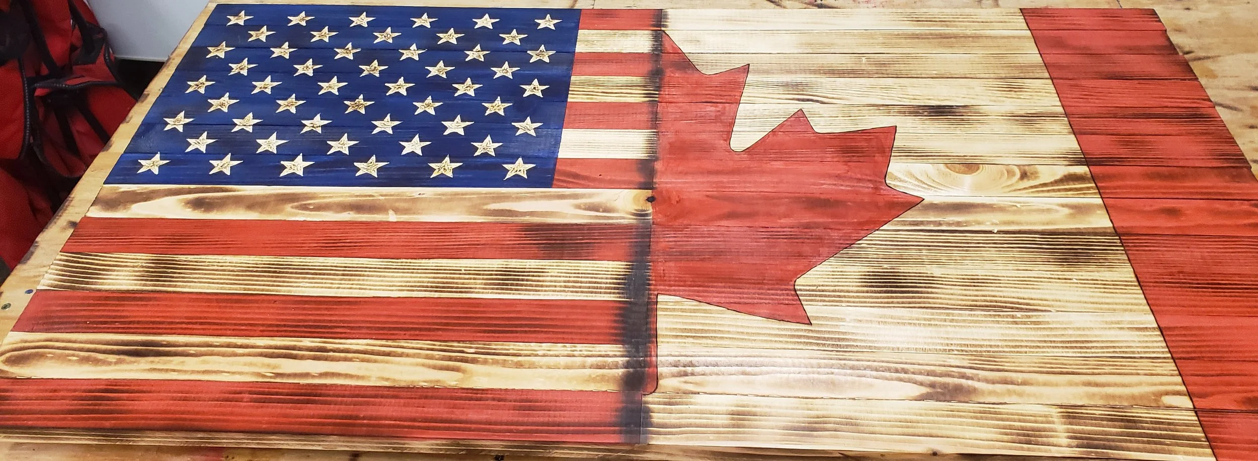 Wooden table painted with a design combining the American and Canadian flags.
