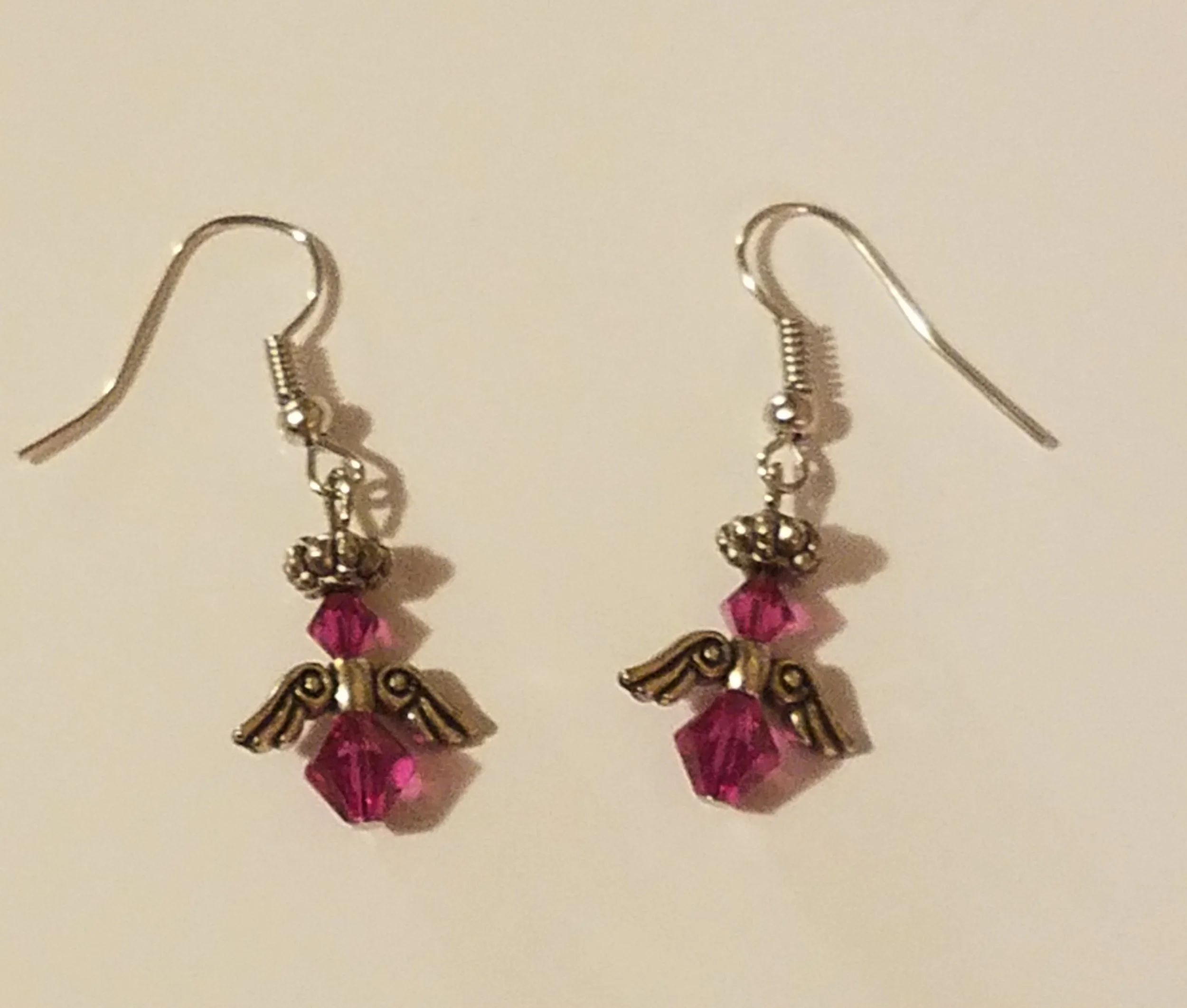 Pink crystal angel earrings with metal wings and hooks.