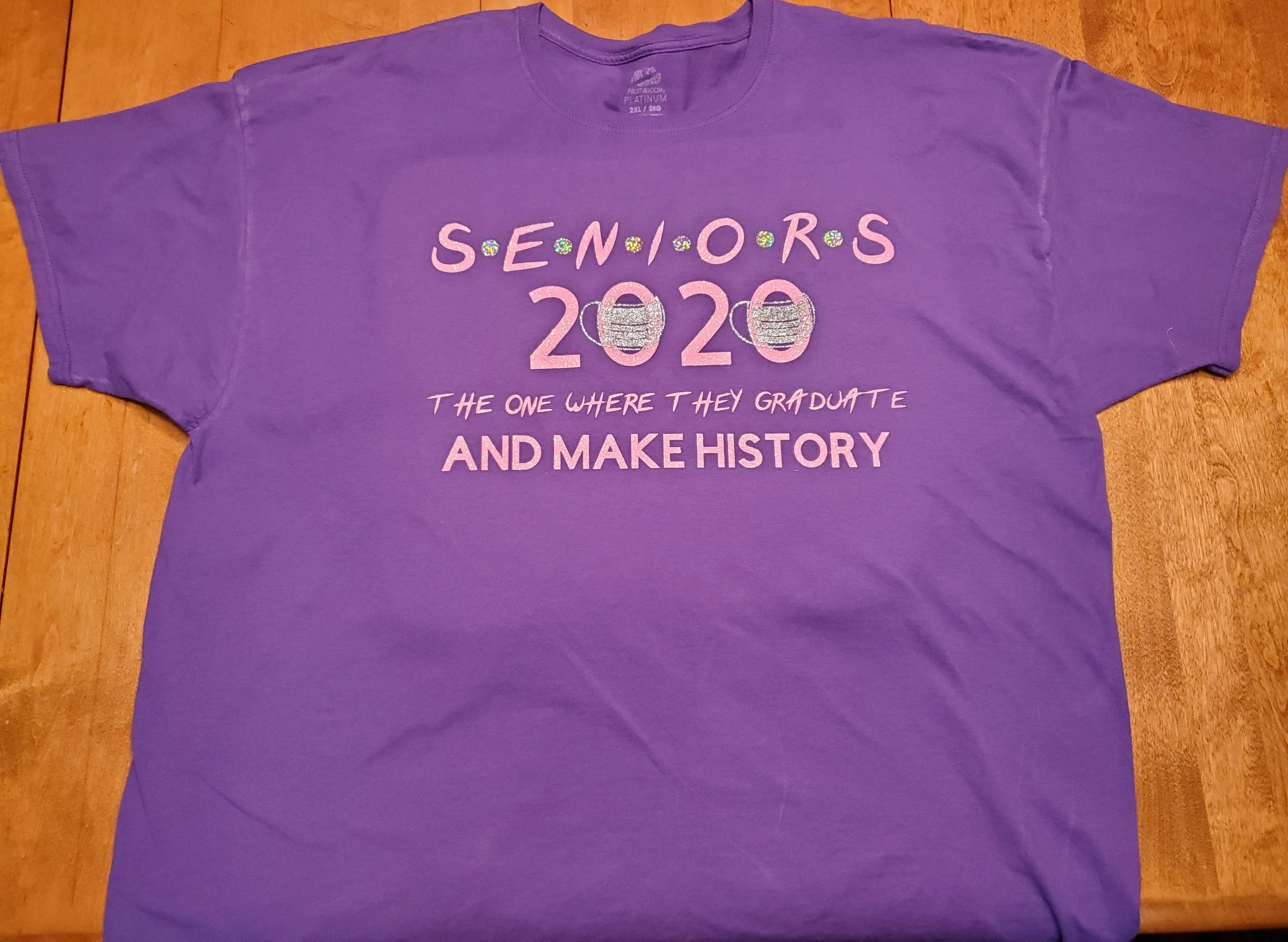 Purple T-shirt with text and graphics celebrating the 2020 senior class graduation, featuring large numbers 2020 with glitter details, a subtitle that reads "The one where they graduate," and a phrase "And make history" at the bottom.