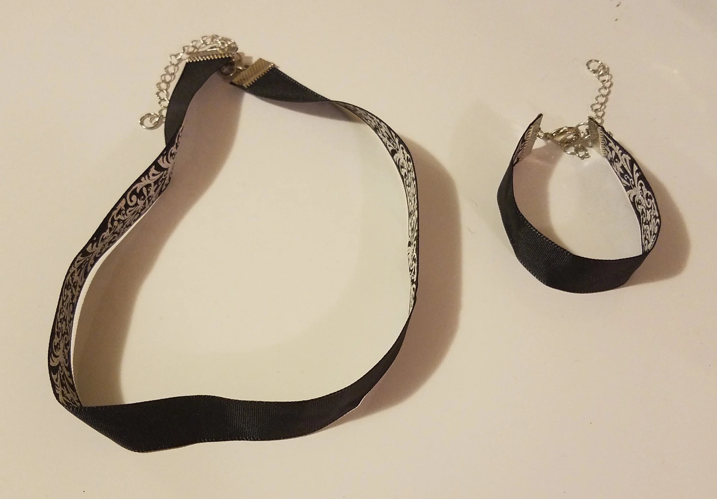 Black and silver choker and bracelet with floral designs on a white background.