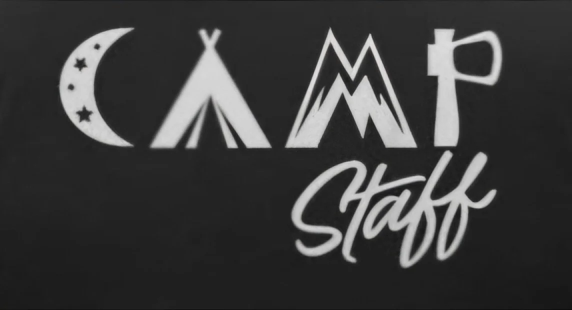Camp staff sign with a crescent moon and stars, tent, mountain, and park symbols, and the word "Staff" in script.