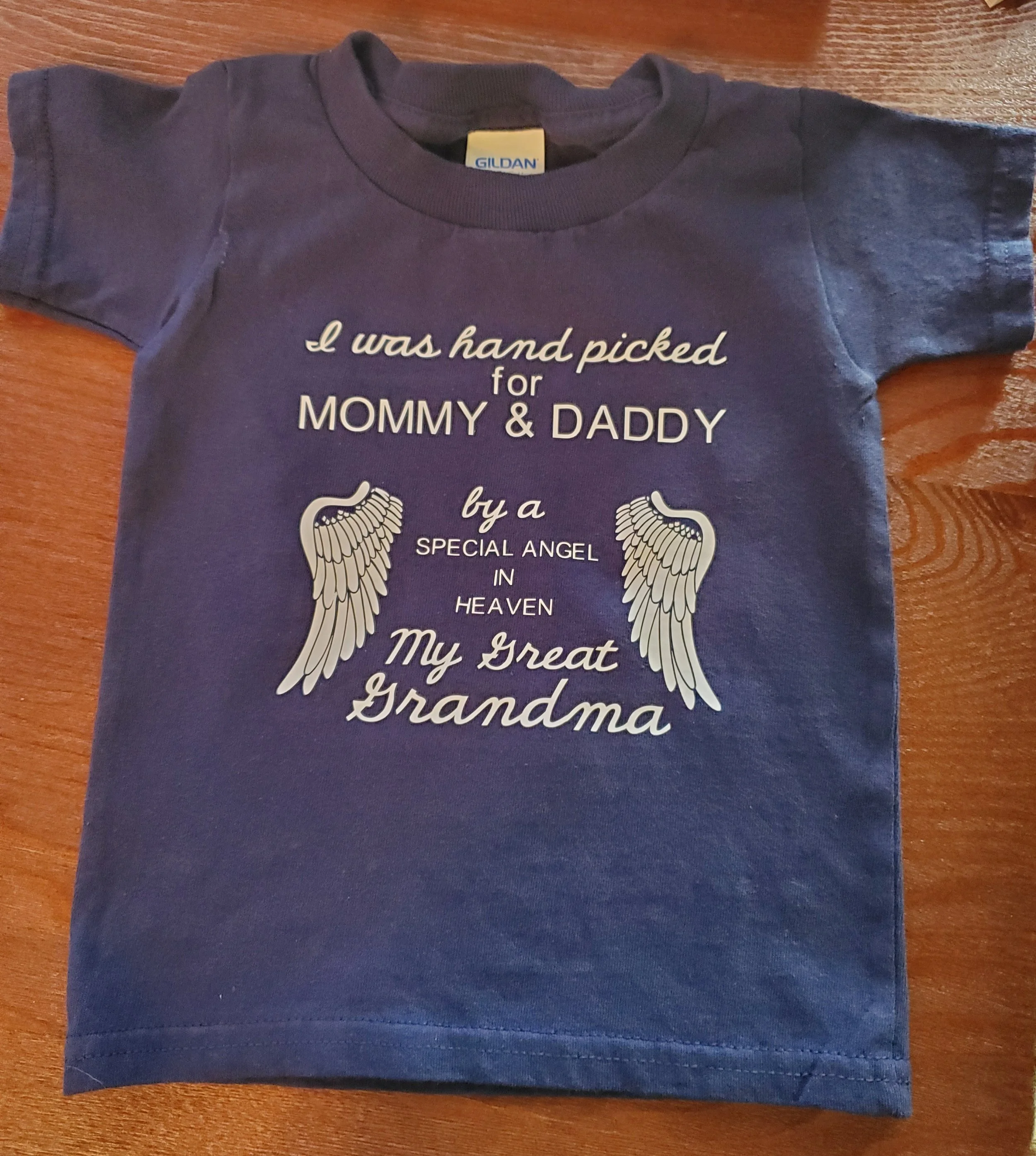 Blue T-shirt with text and angel wings graphic that reads, 'I was hand picked for mommy & daddy by a special angel in heaven. My great grandma.'