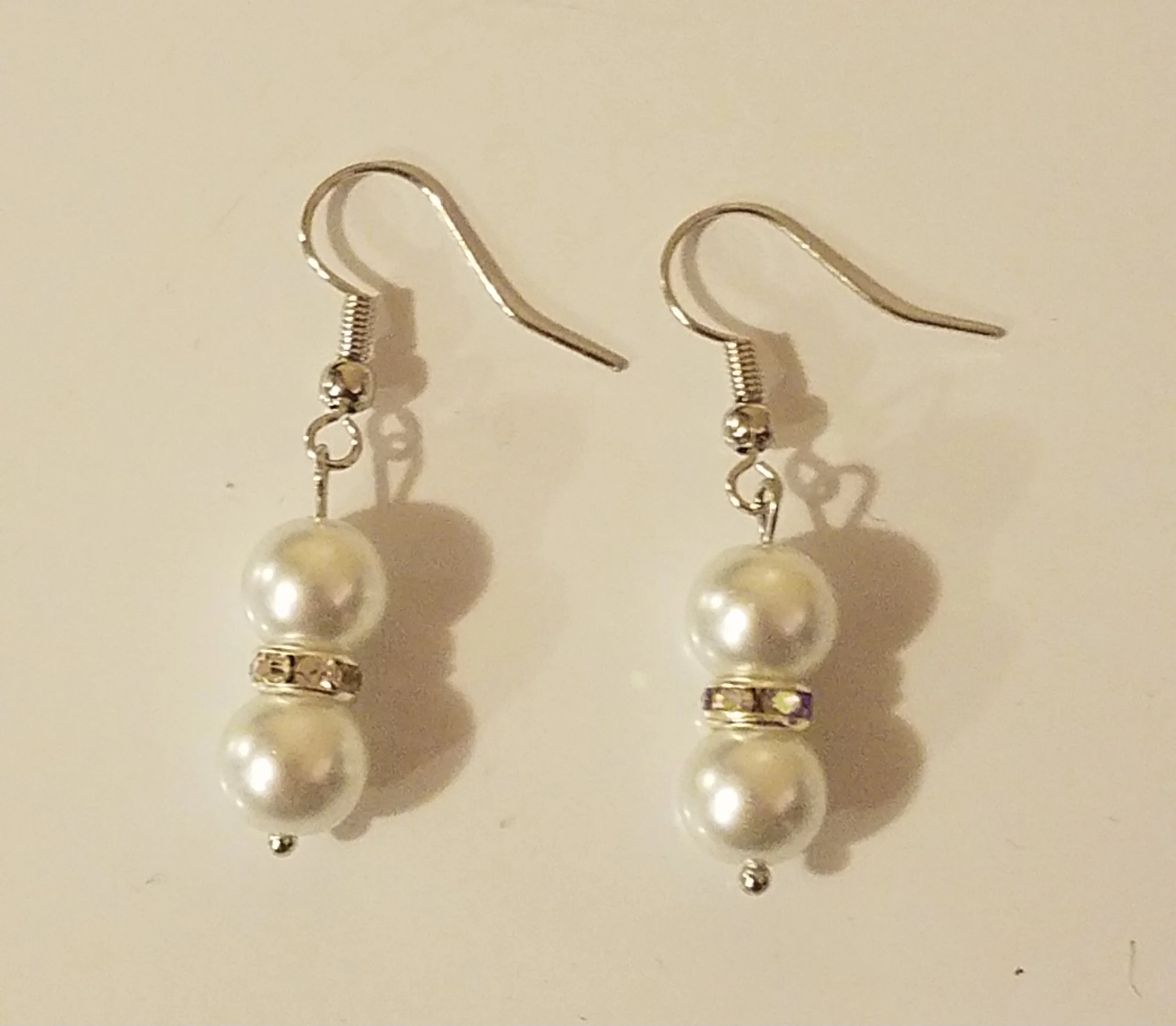 Silver earrings with two pearls and a decorative band in the middle.