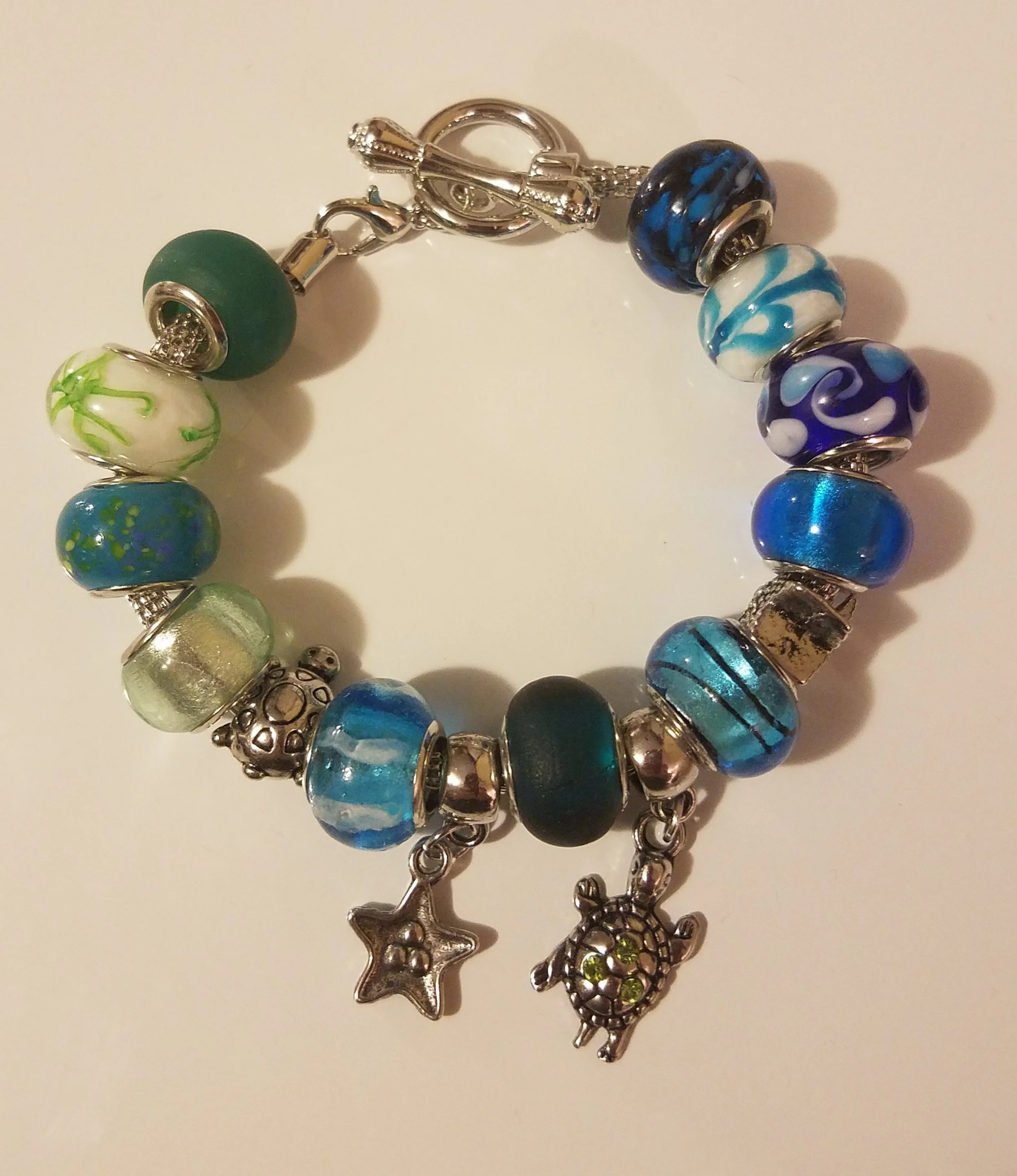 A beaded charm bracelet with colorful glass beads and two dangling charms, one star and one turtle.