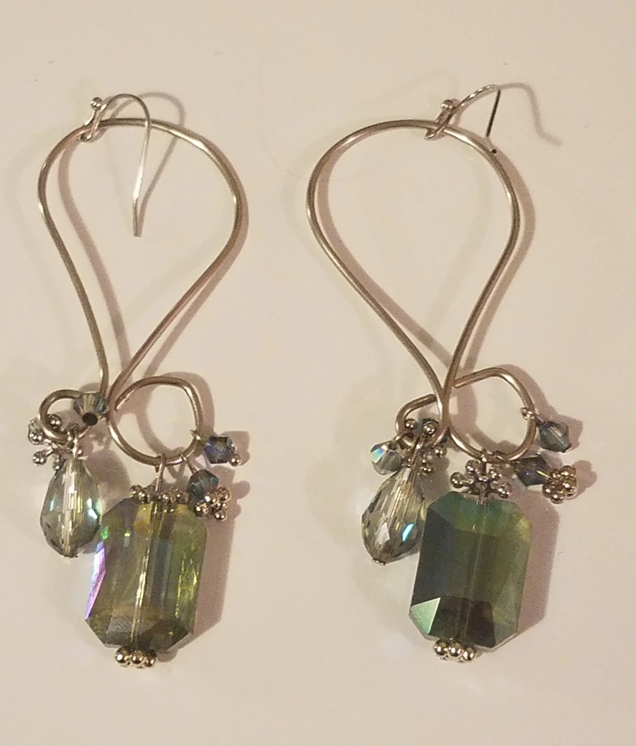 Silver earrings with dangling green, clear, and iridescent crystals.