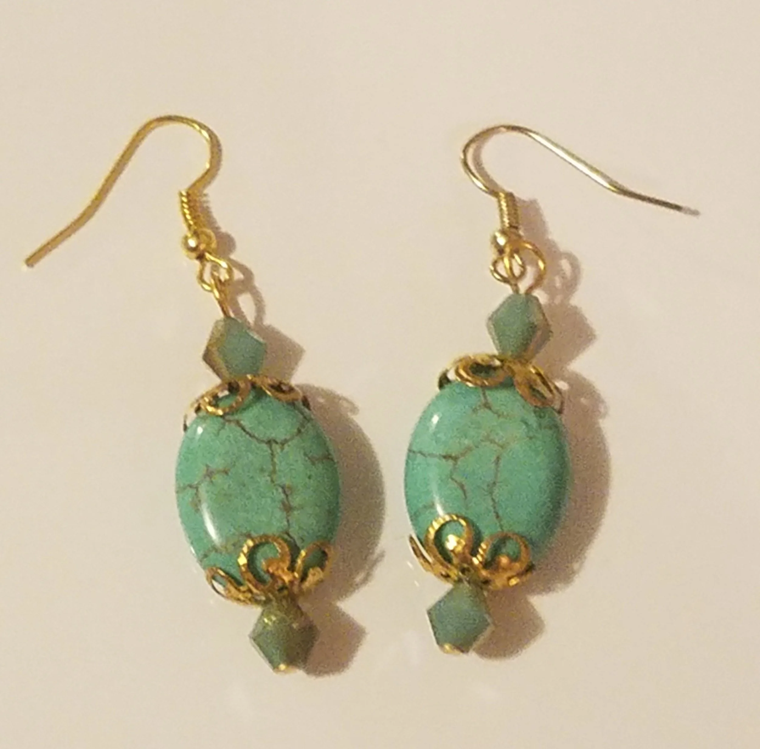 Gold earrings with turquoise beads and geometric accents.
