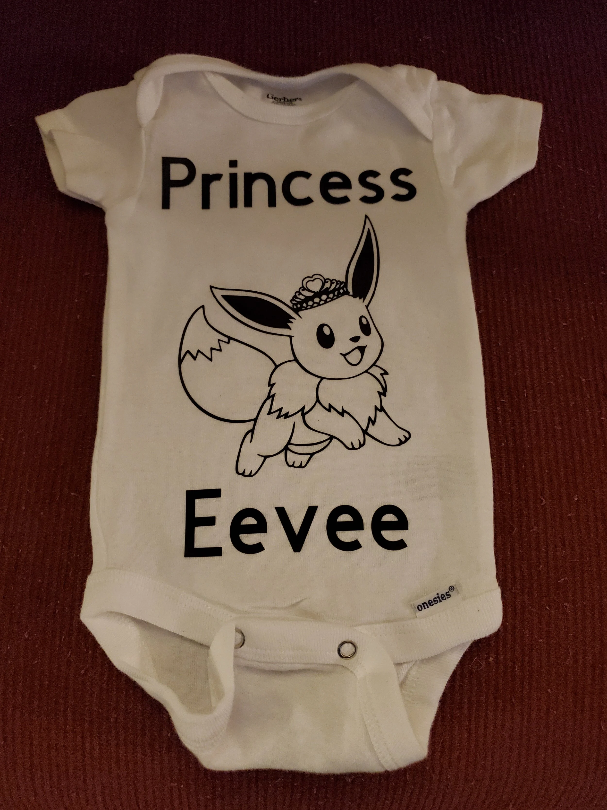 White baby onesie featuring a drawing of Eevee, a Pokémon, with the words 'Princess Eevee' printed above and below the illustration.