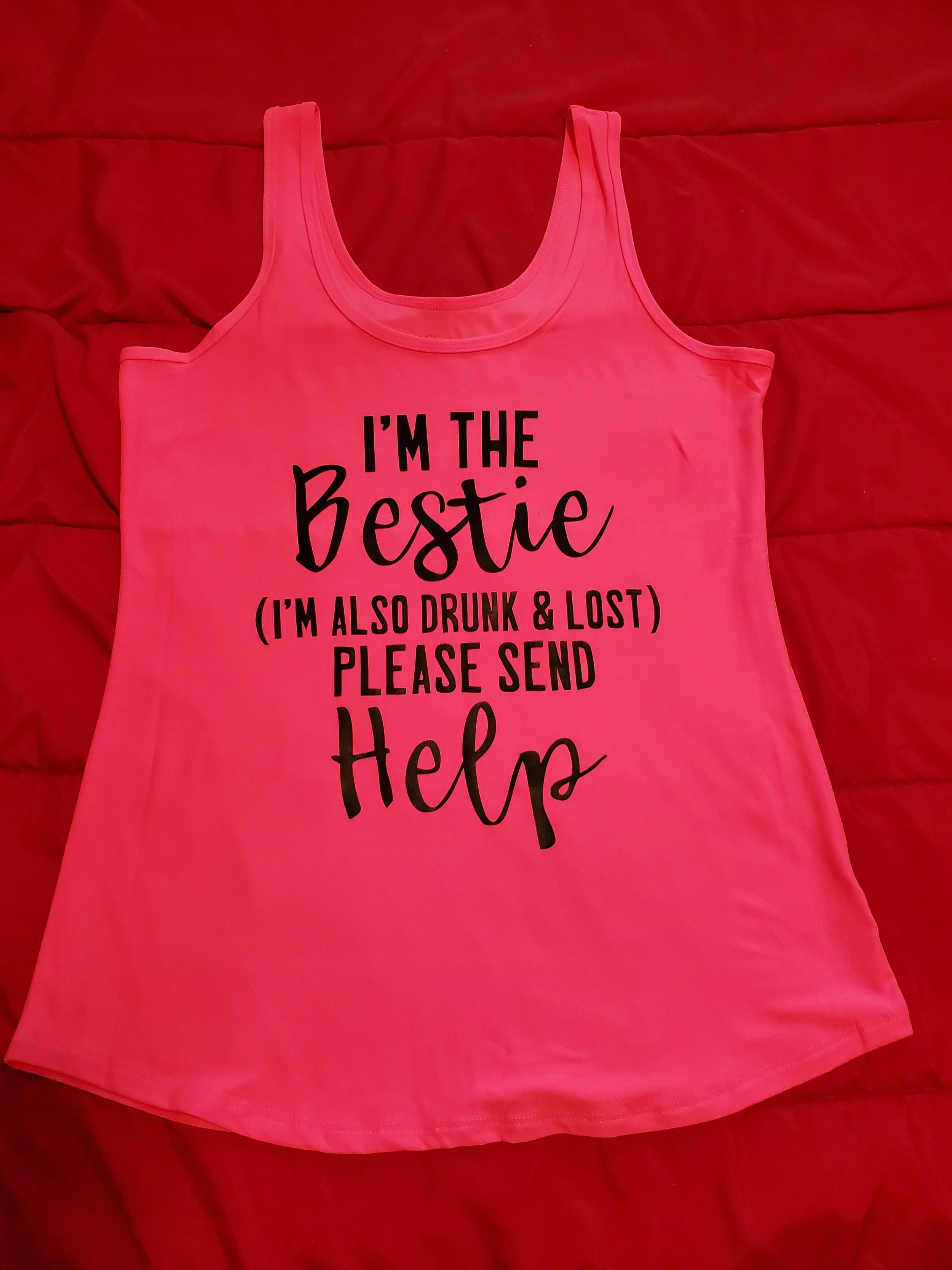 Pink tank top with black text that reads, "I'm the bestie (I'm also drunk & lost) please send help" on a red background.