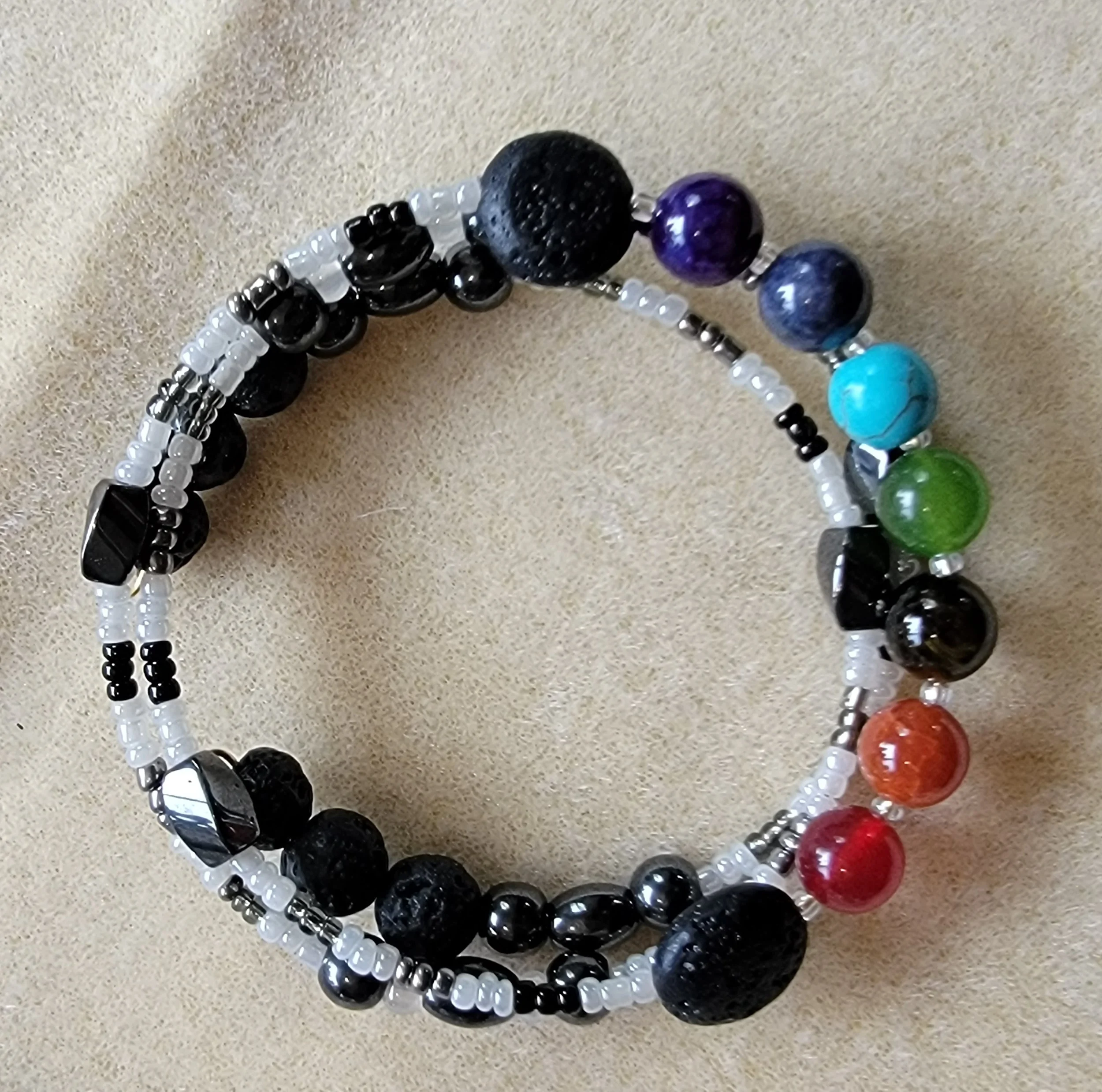 Colorful beaded bracelet with black, white, and multicolored stones on a beige background.