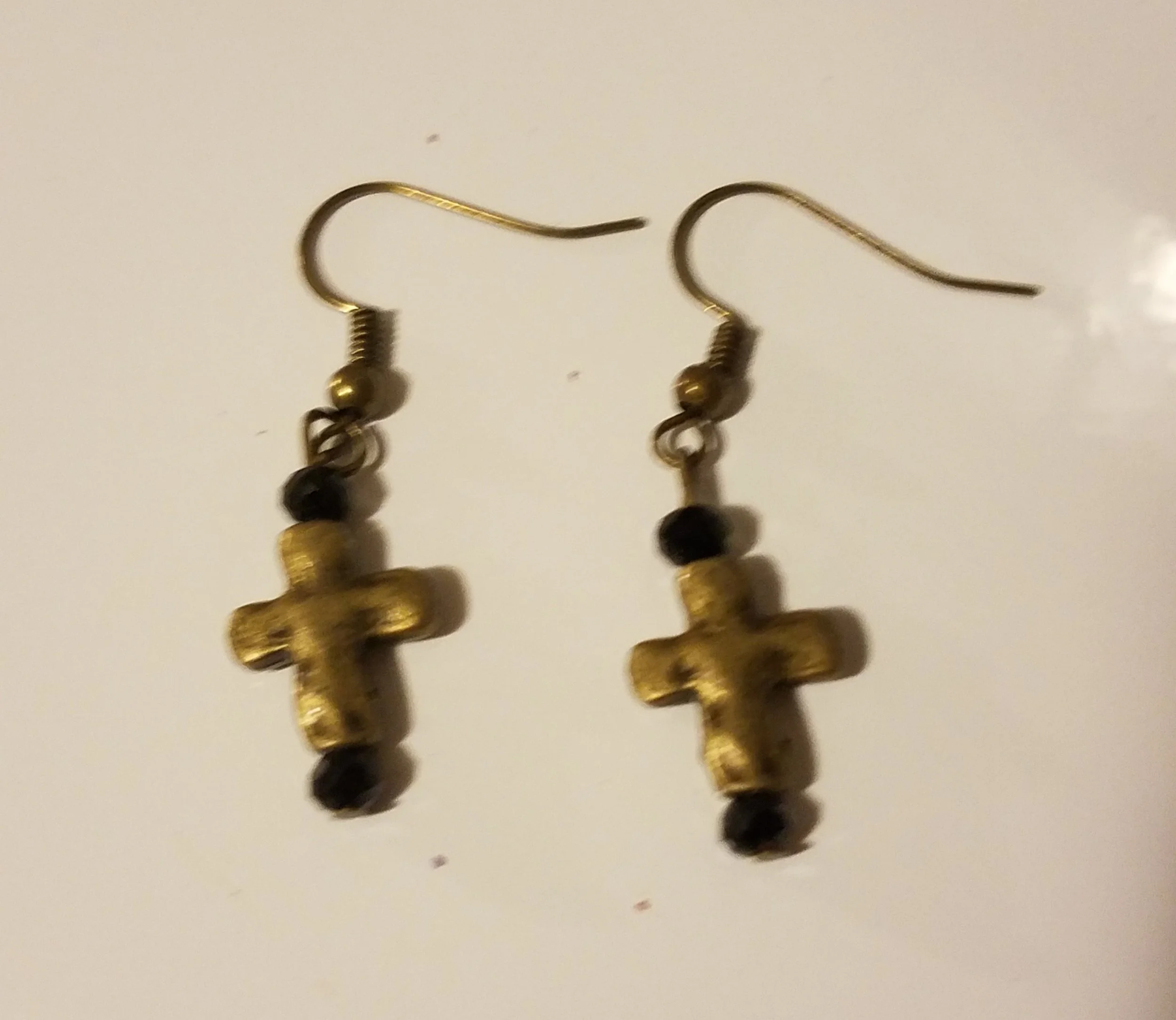 Gold cross earrings with black beads on white background.