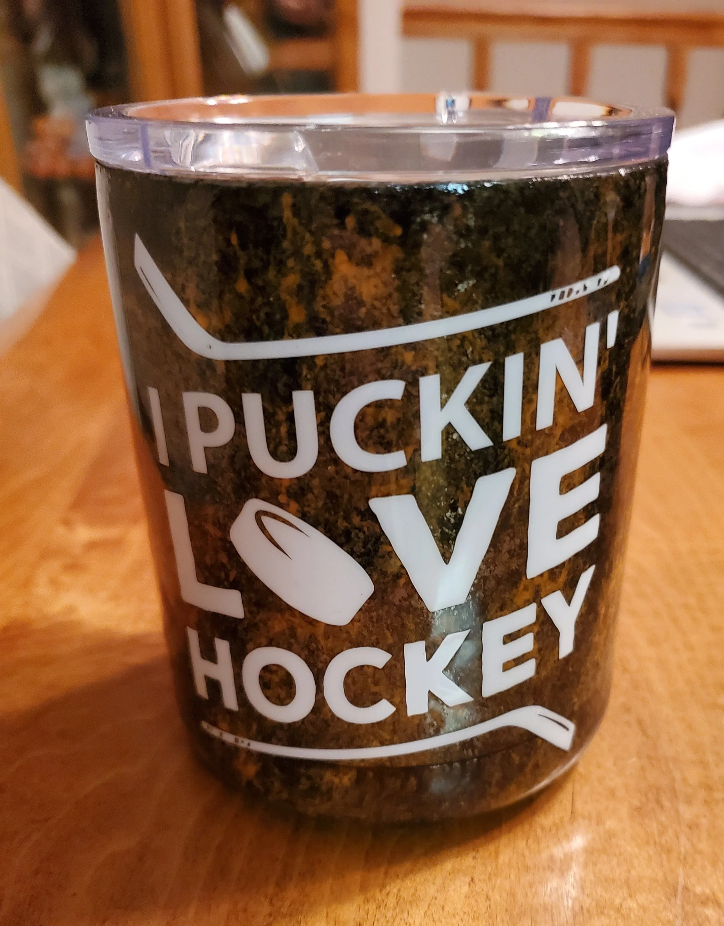A mug with a dark marbled design and a clear plastic lid. The mug has white text that reads 'I PUCKIN' with a hockey puck graphic and 'LOVE HOCKEY' below.