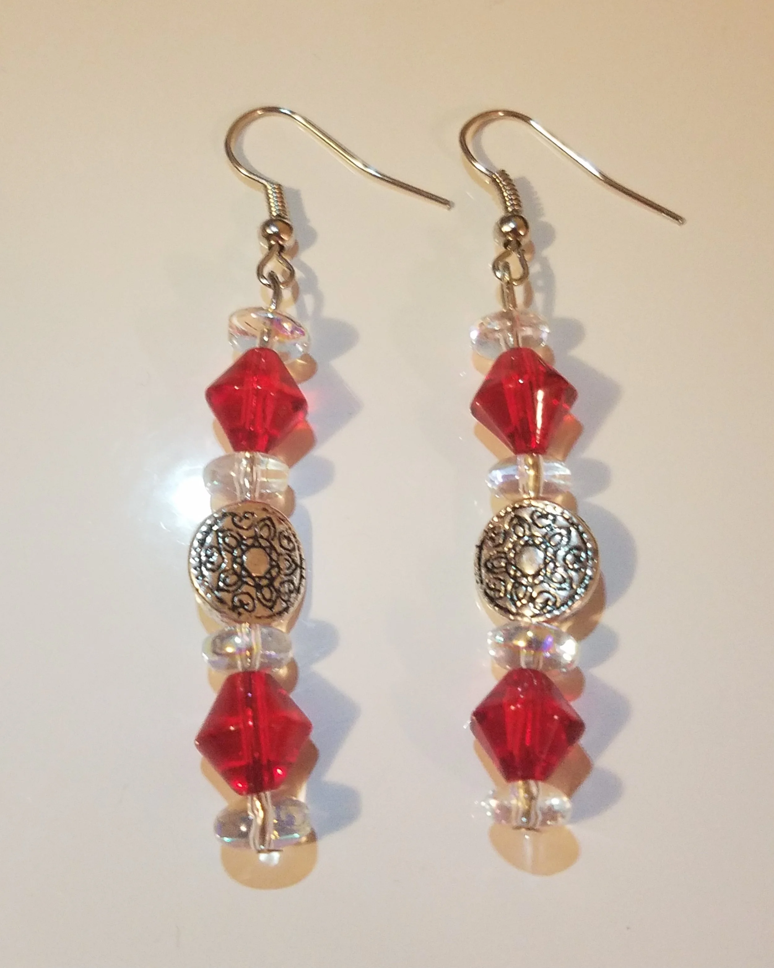 Red and clear beaded dangle earrings with ornate silver embellishments.