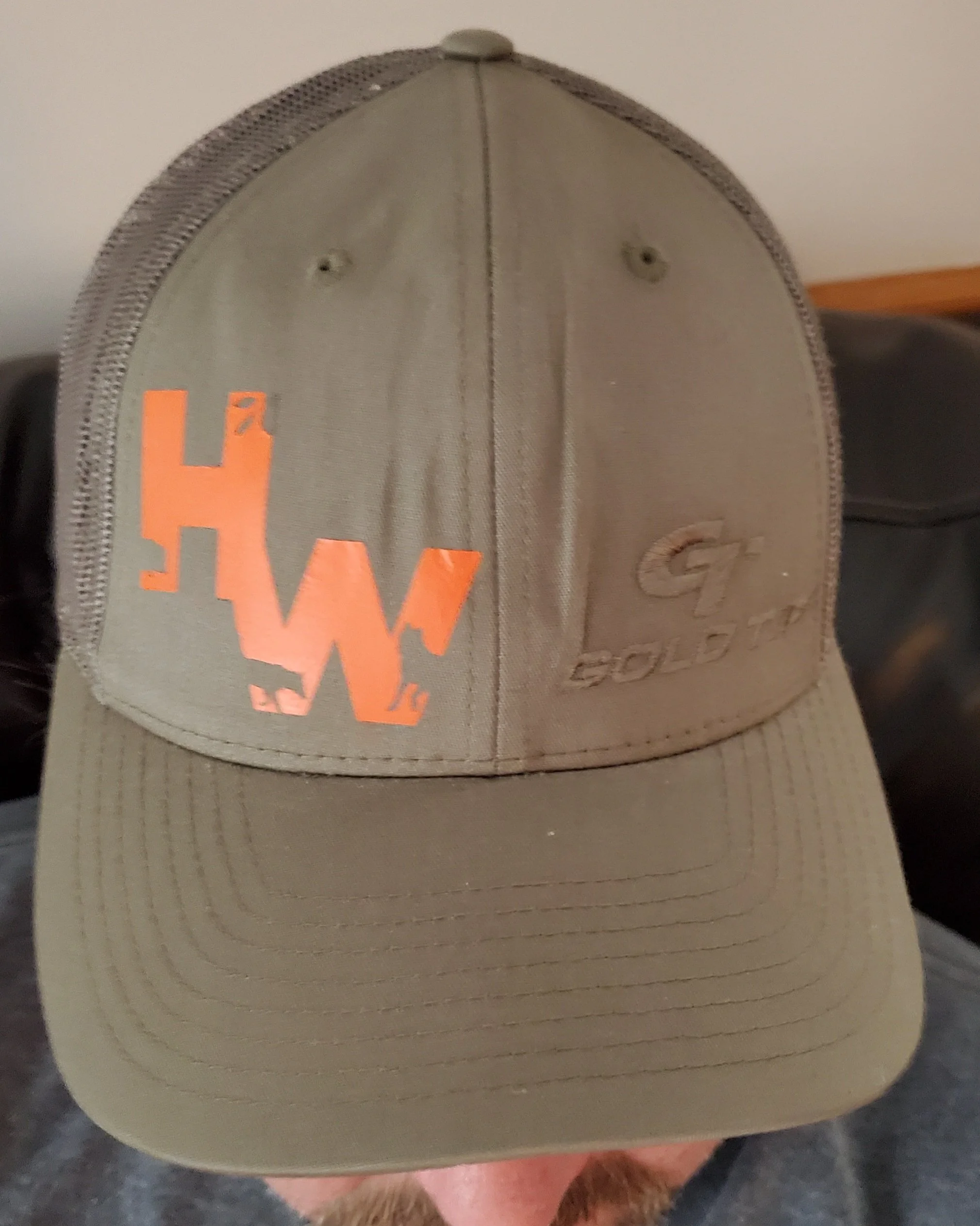 A tan baseball cap with an orange and black 'H' logo and the word 'GOLD G' embroidered on the front.