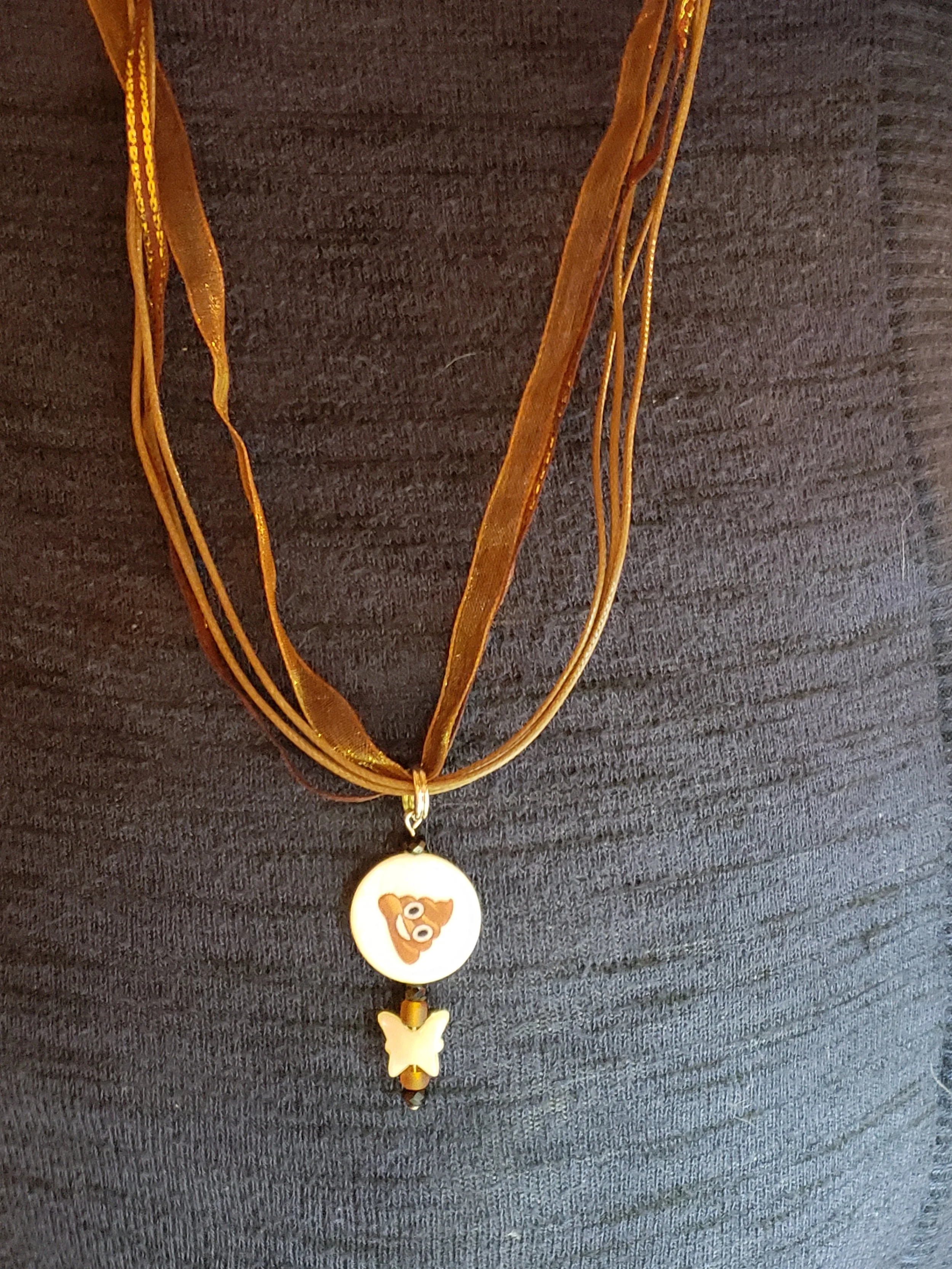 A necklace with multiple brown ribbons, a round pendant with a cartoon dog face, and a butterfly-shaped charm hanging below
