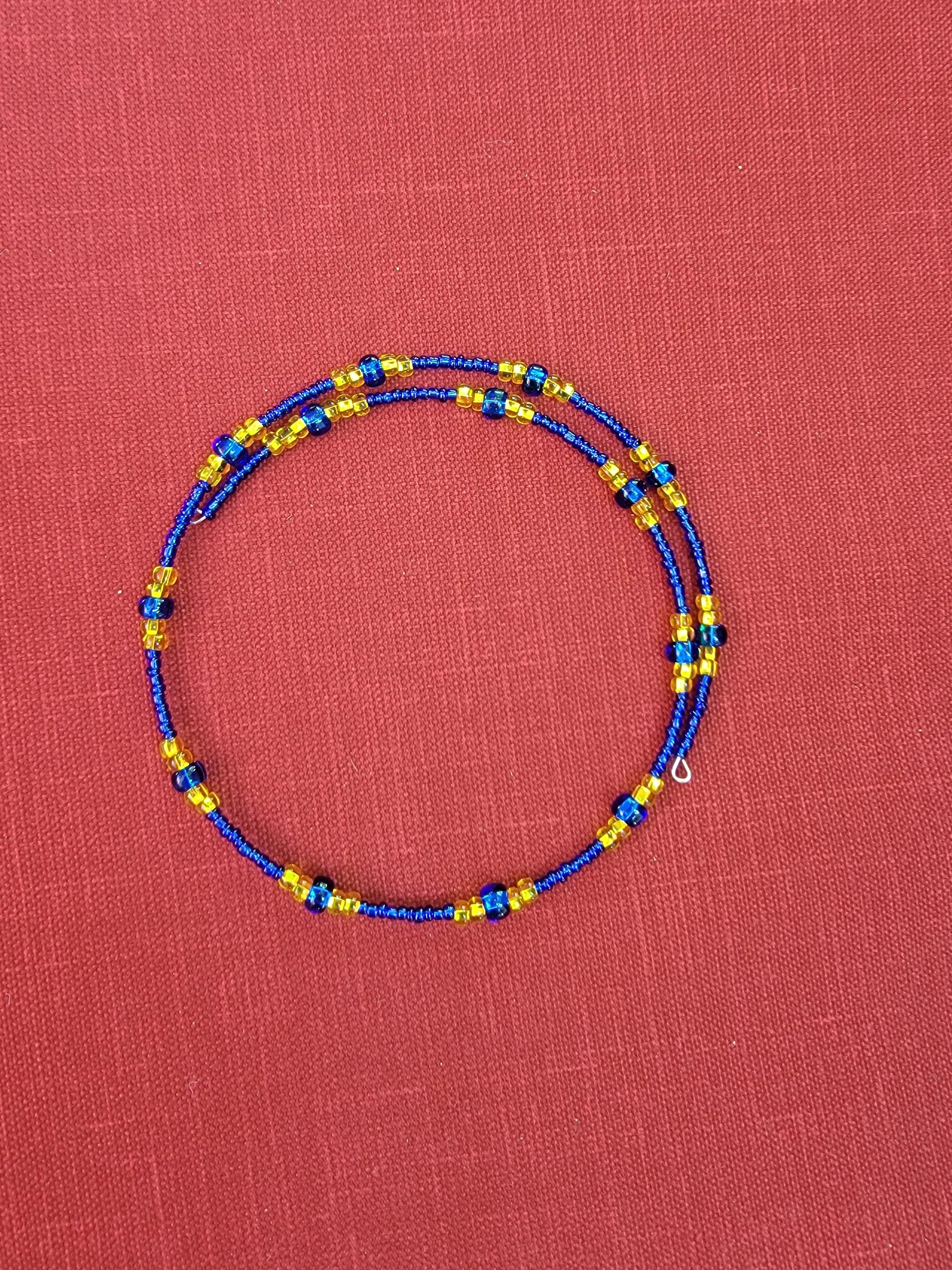Blue and yellow beaded necklace on a red fabric background.