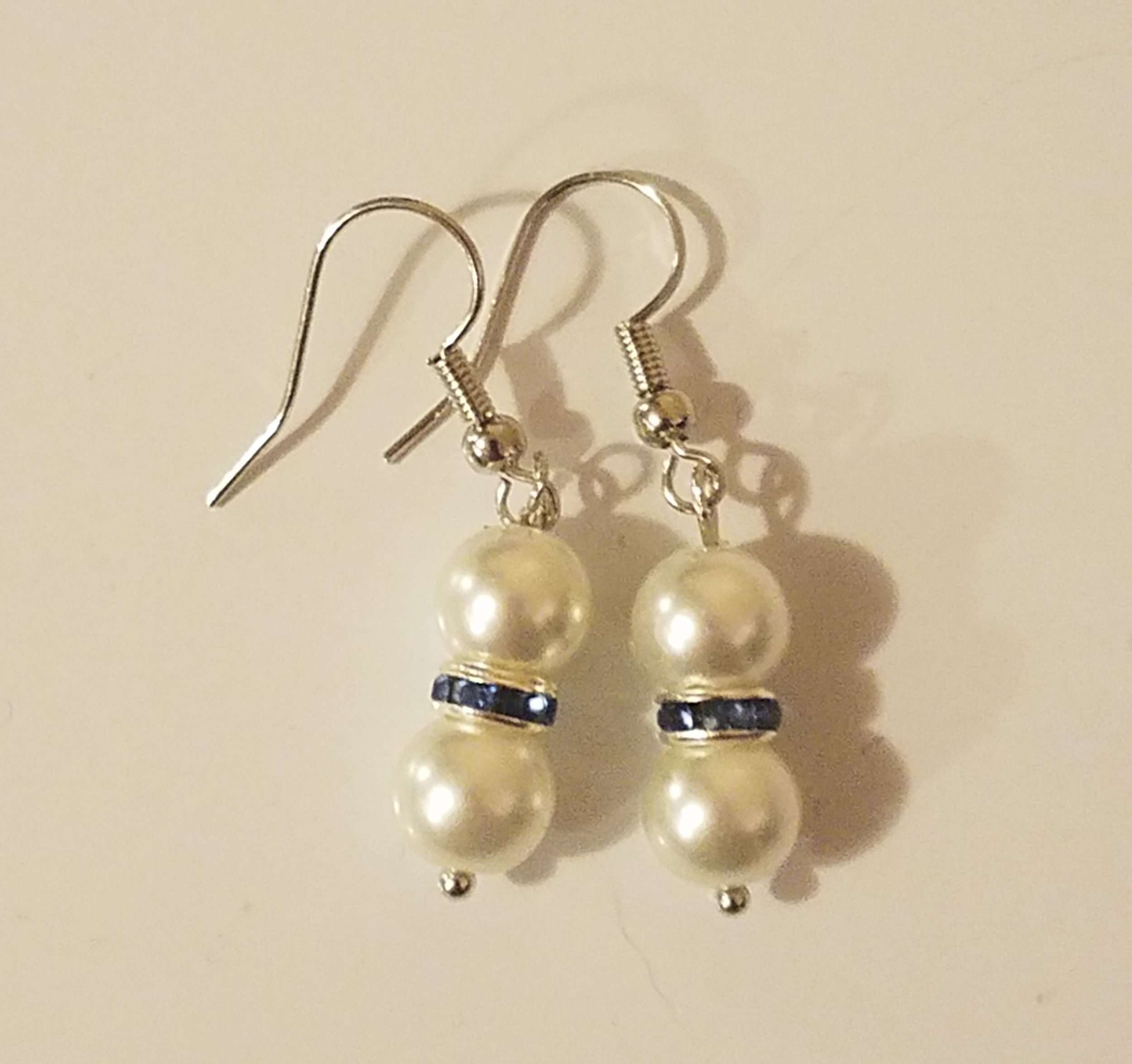 Silver earrings with pearl beads and a blue gemstone in the middle.
