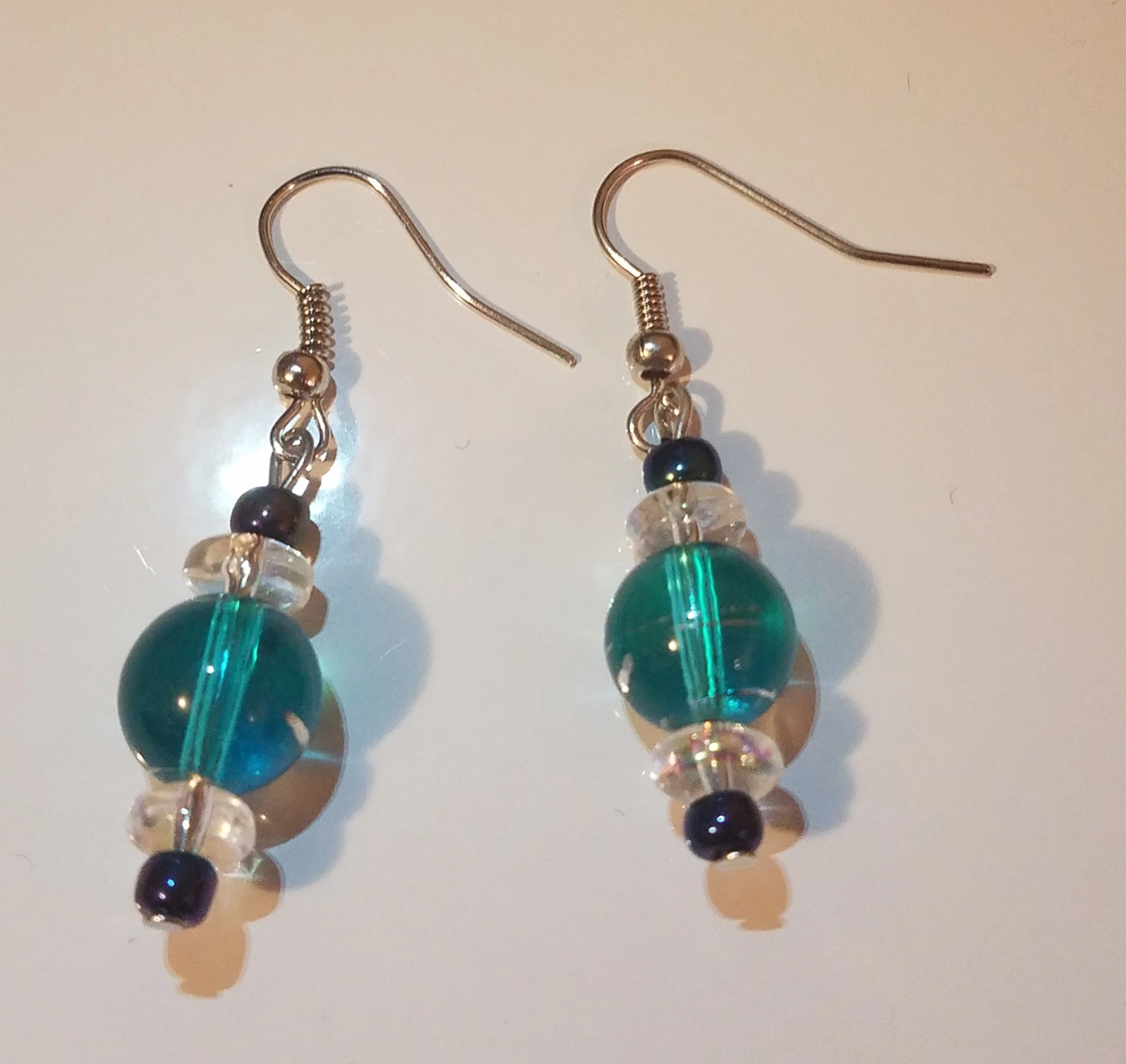Pair of dangling earrings with multicolored glass beads on a white surface.