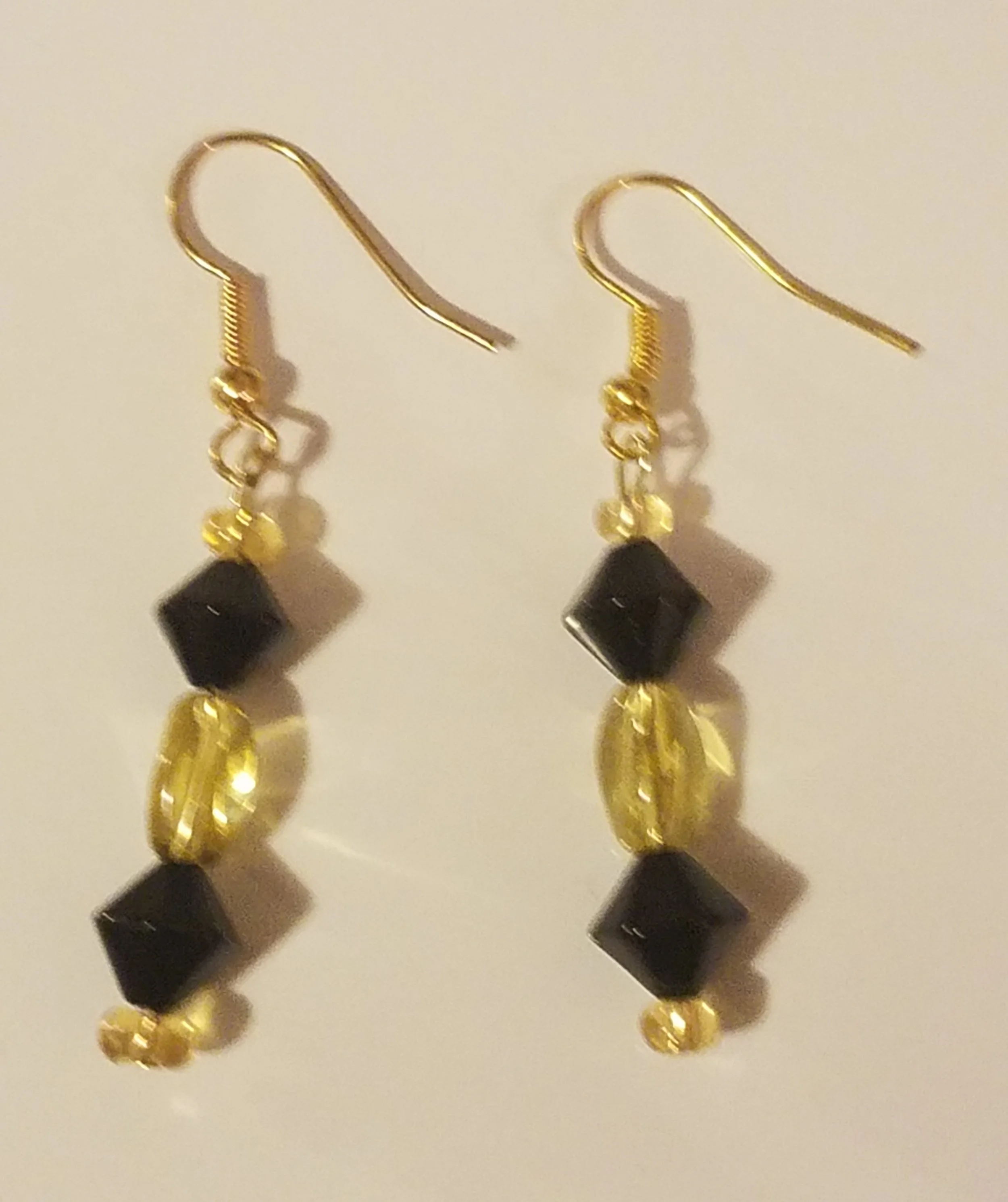 Gold earrings with black beads and gold oval accents.