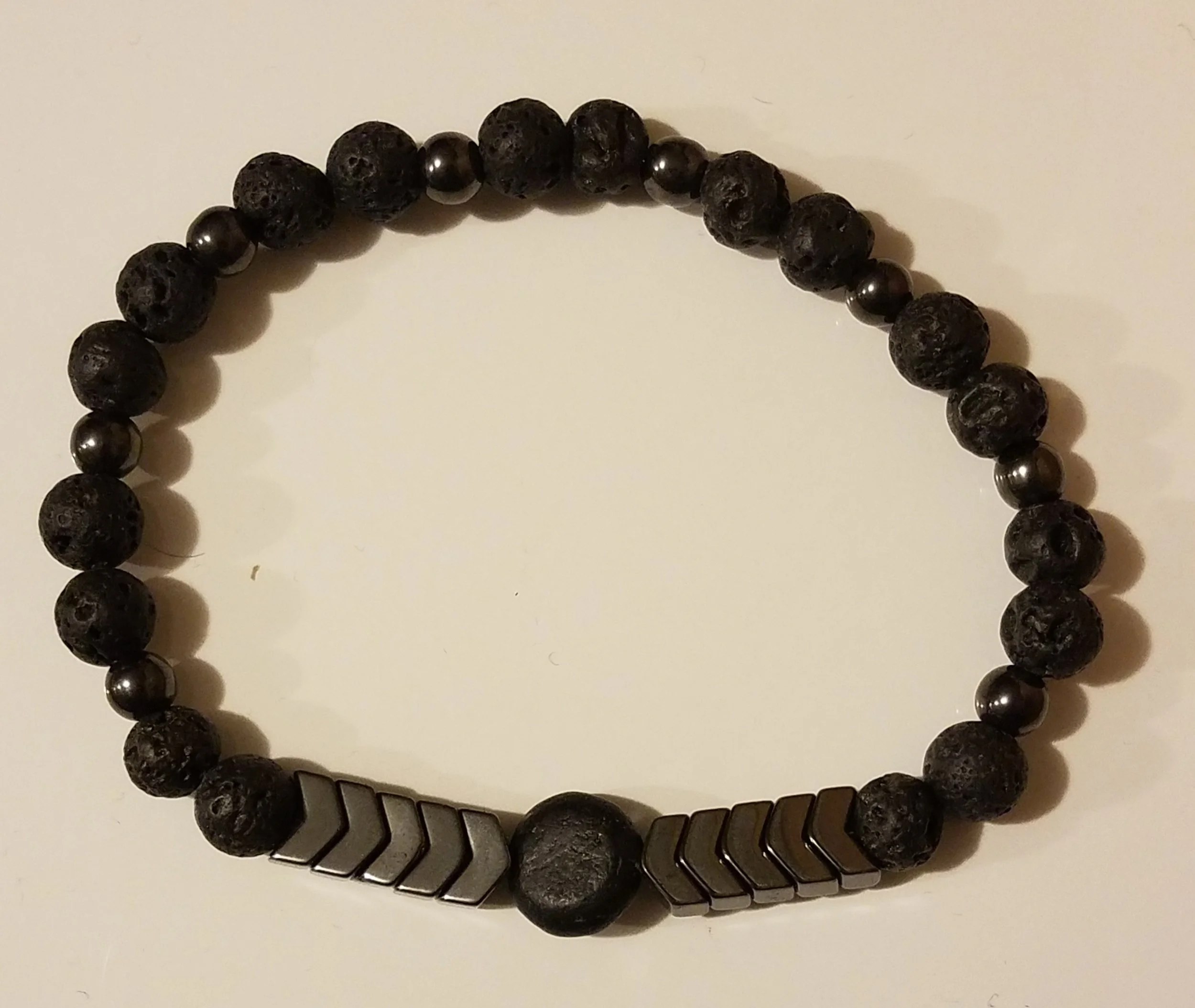 Black beaded bracelet with metallic arrow-shaped accents and a large round bead in the center.