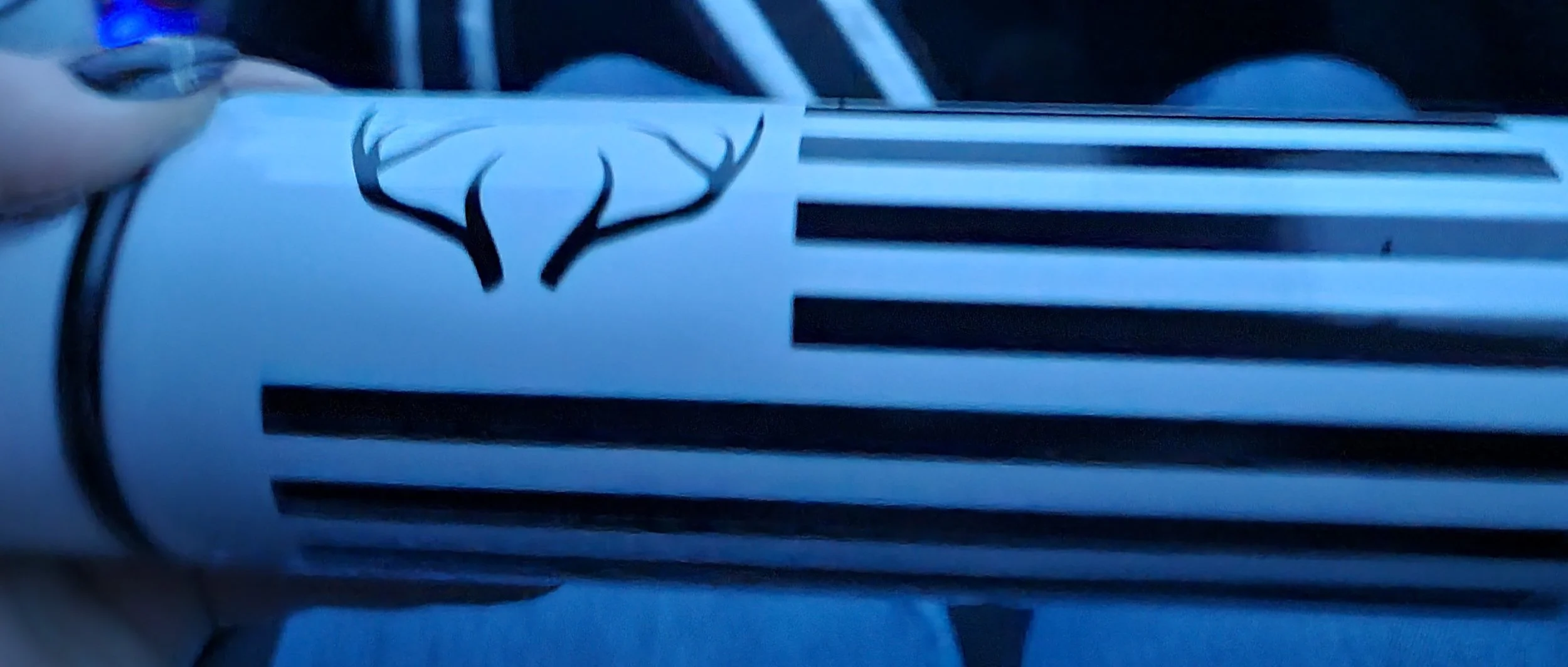 A close-up of a white object with black horizontal stripes and a black deer head silhouette logo.