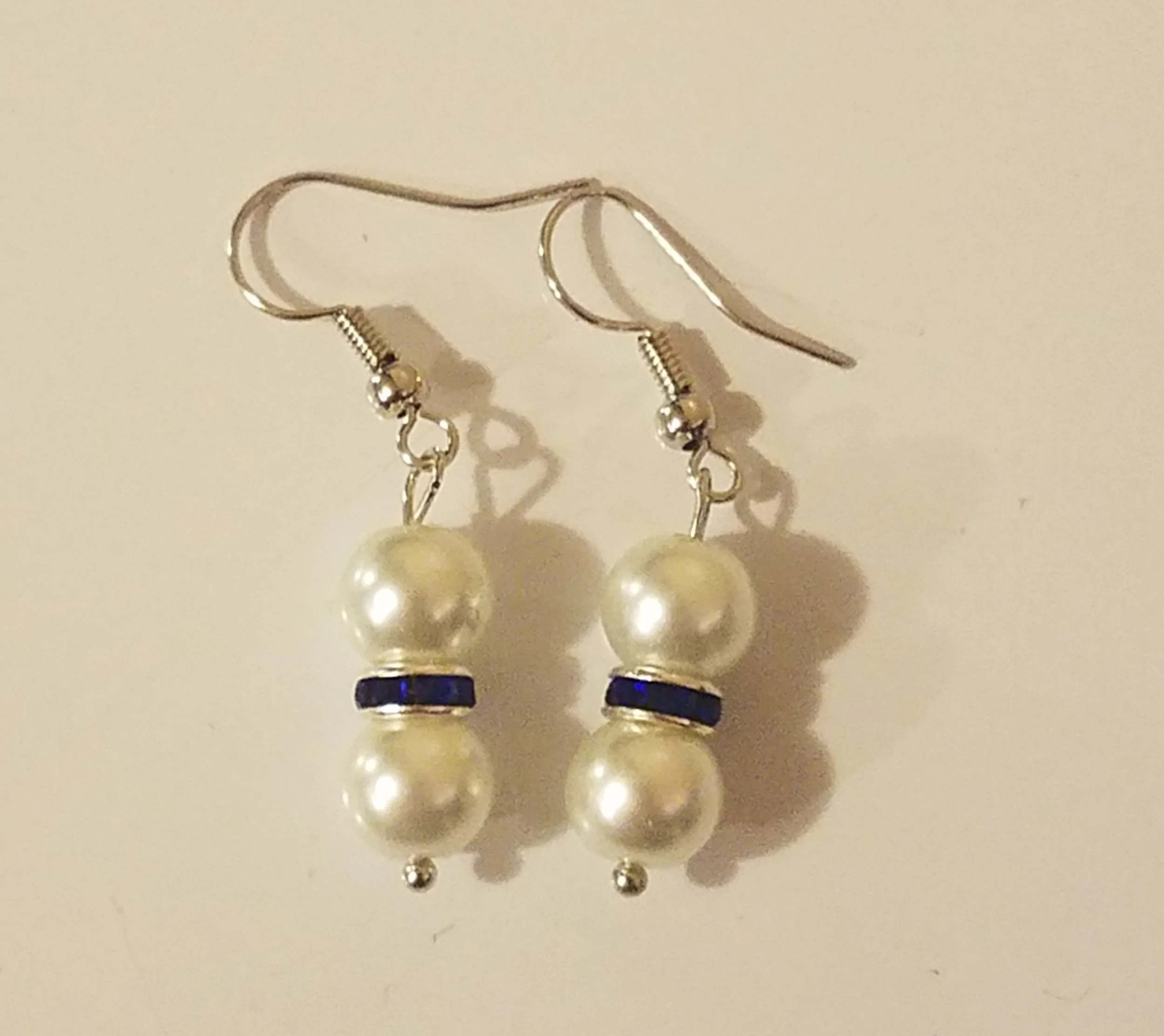 Earrings with large pearls and blue gemstone accents.