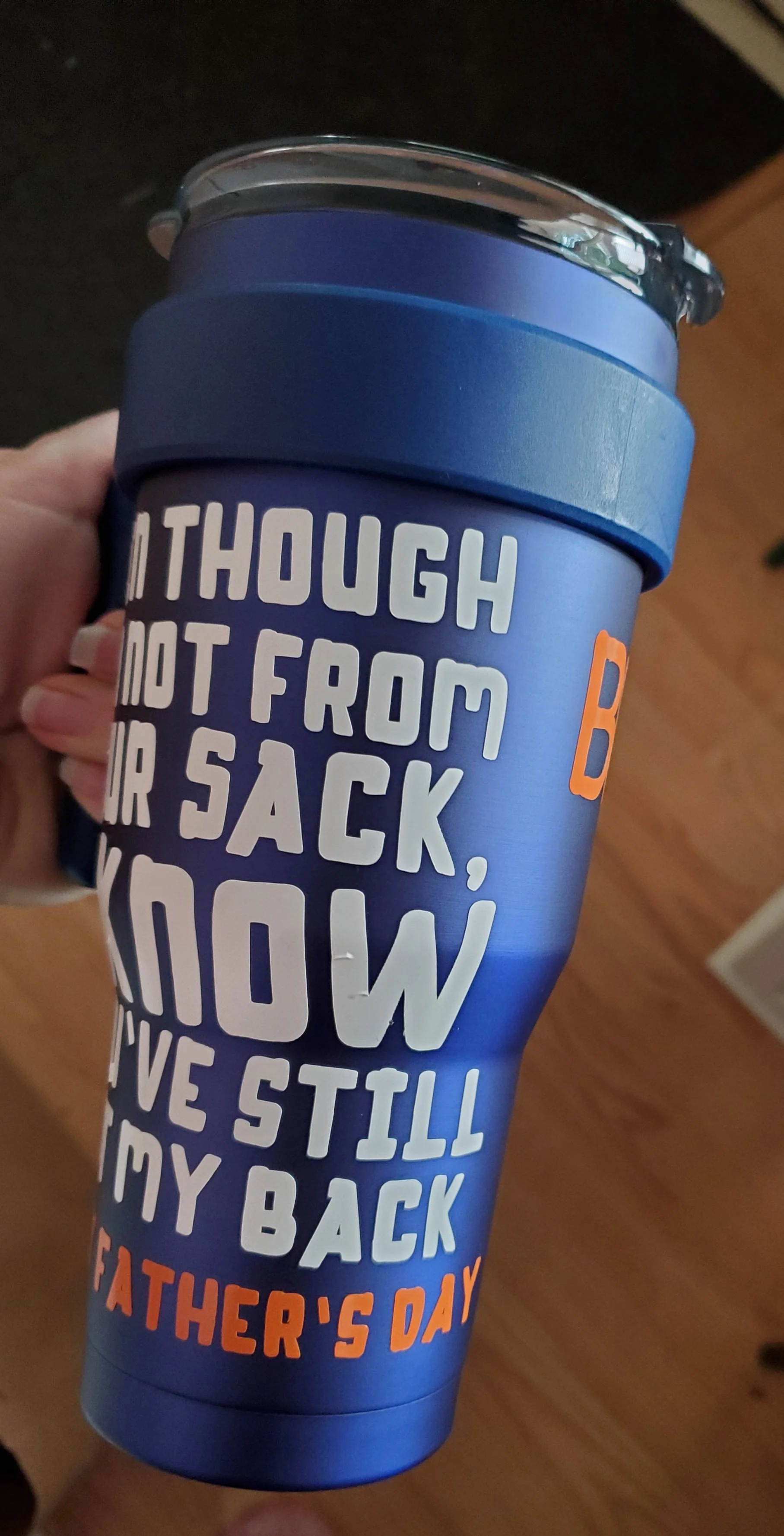 A blue travel mug with a lid, featuring a Father's Day message in white and orange text that reads, "Although not from your sack, wow, I still love my back, Father's Day."