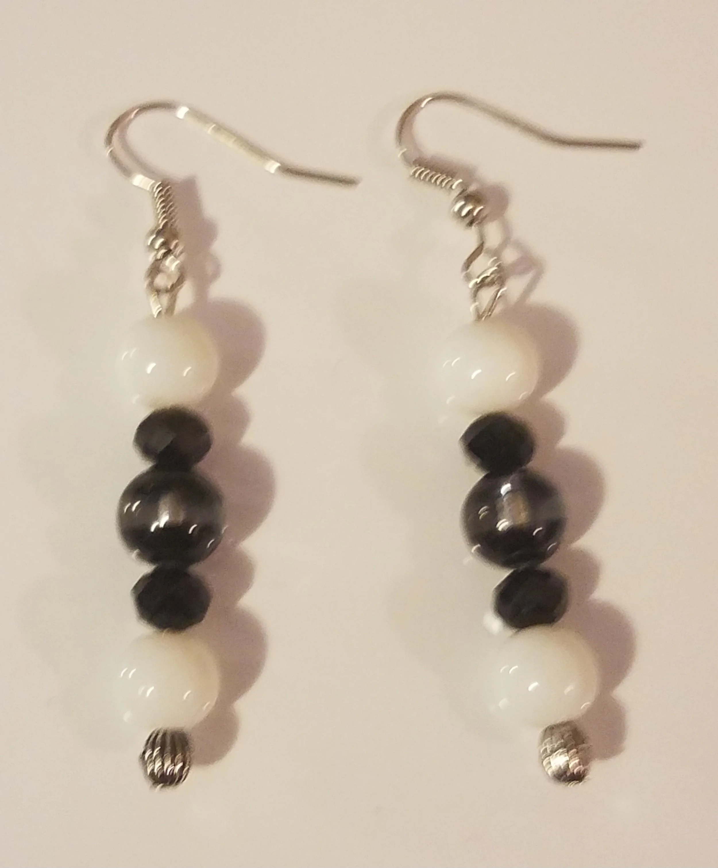 Pair of dangling earrings with alternating black and white beads on silver hooks.