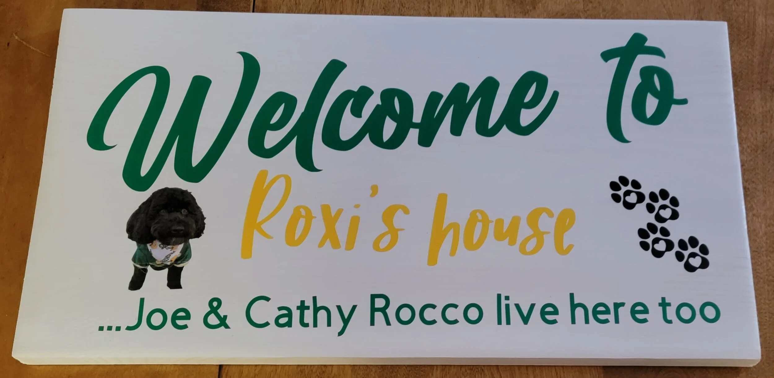 Welcome sign for Roxy's house with a picture of a black dog, paw prints, and text indicating Joe and Cathy Rocco live there.