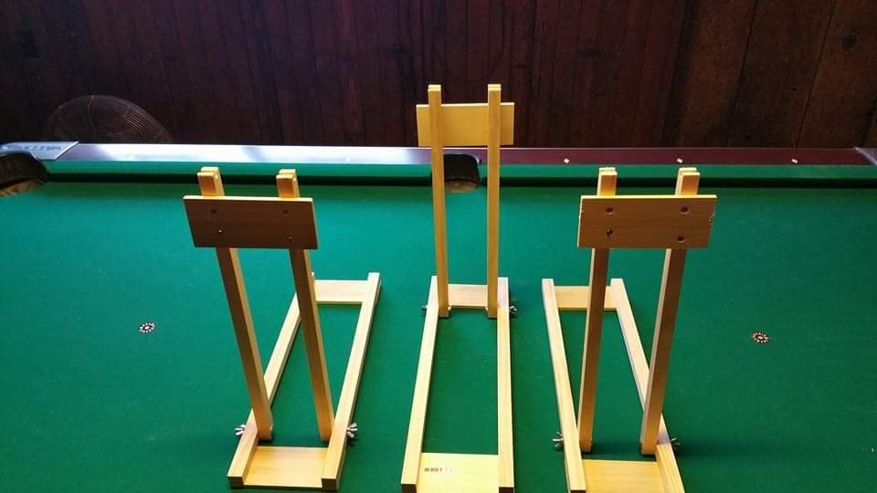 Three wooden easels standing upside down on a green pool table.