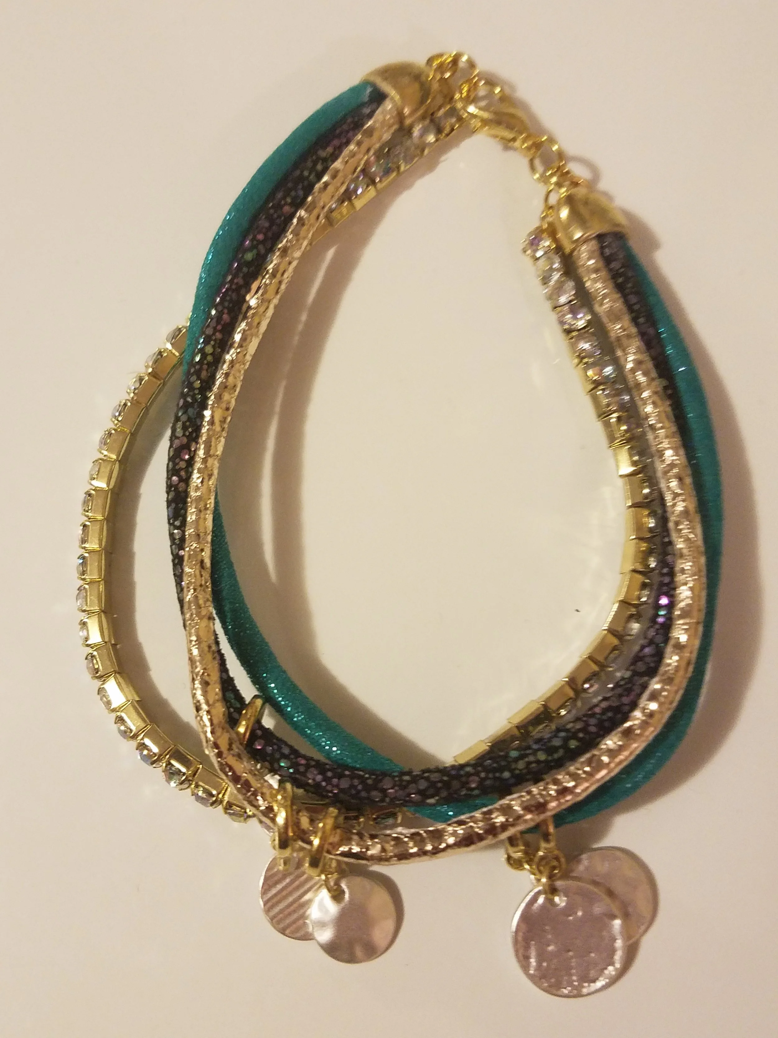 A set of colorful, layered bracelets with gold accents and dangling coin charms.