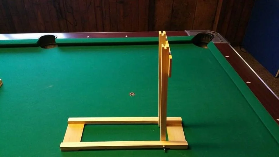 A shuffleboard court with a wooden shuffleboard scorer and a small, circular, multicolored puck mid-play.