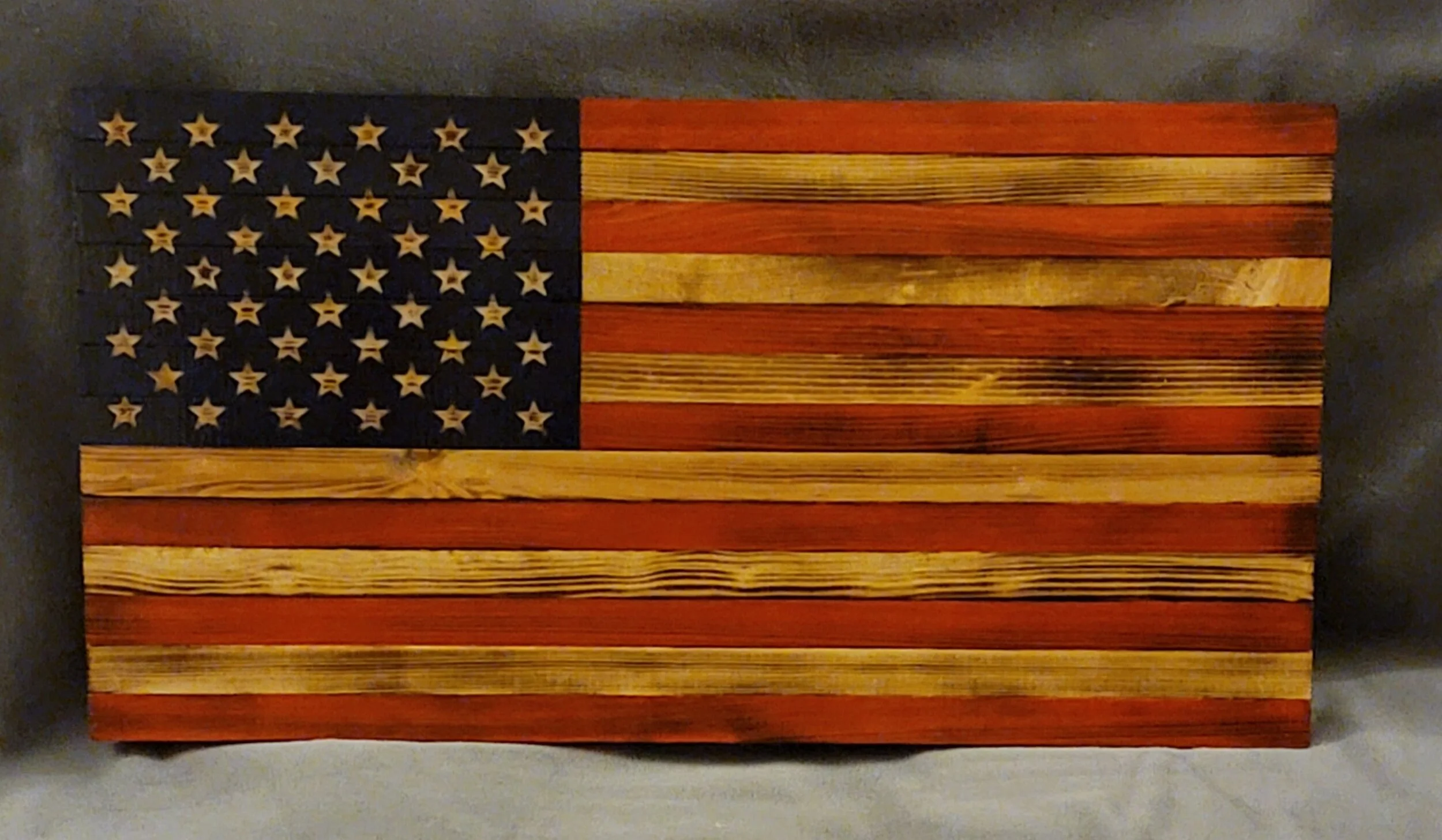 Wooden American flag wall art with distressed finish, featuring stars on a dark blue field and red and wood-colored stripes.