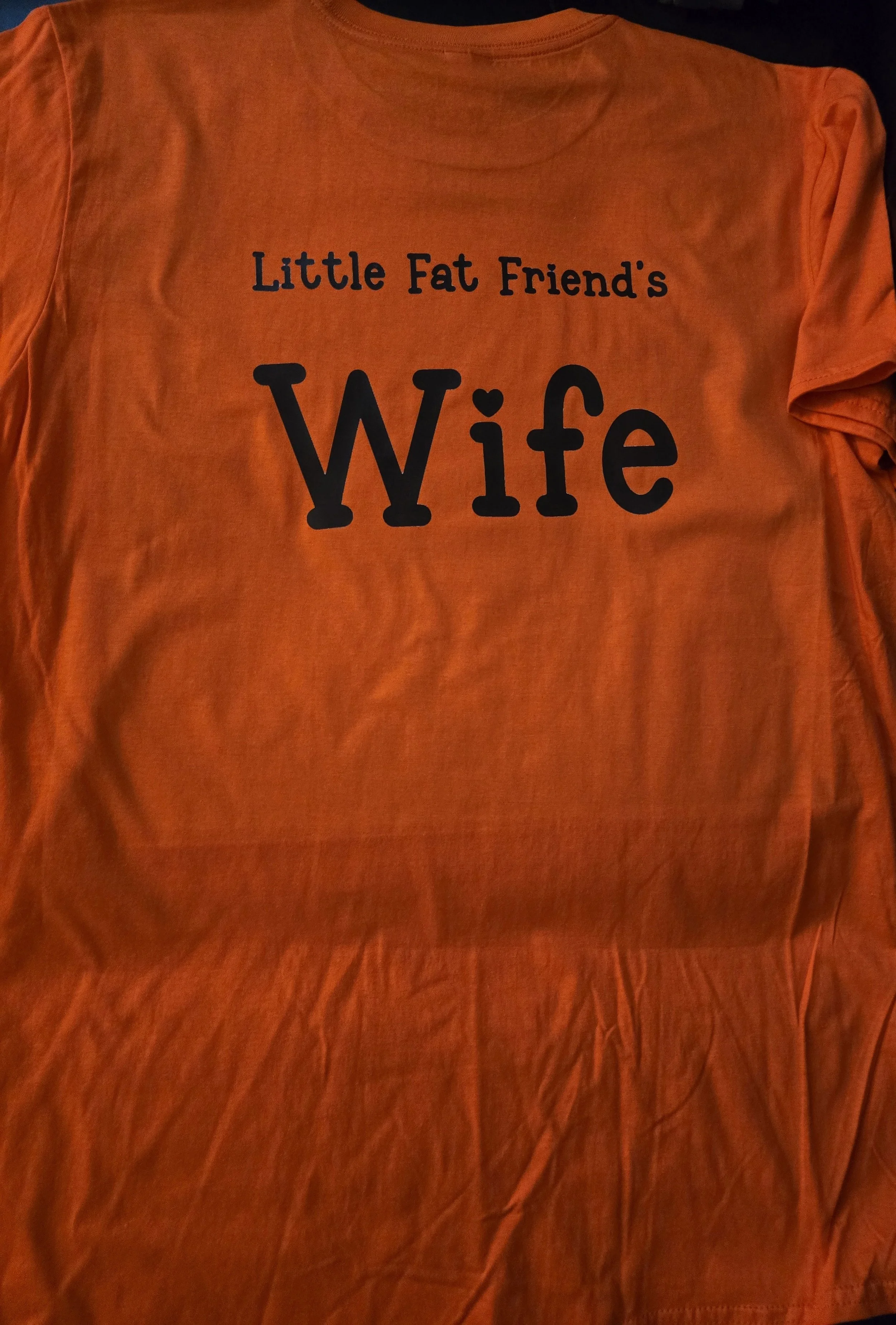 Orange t-shirt with black text that reads 'Little Fat Friend's Wife'.