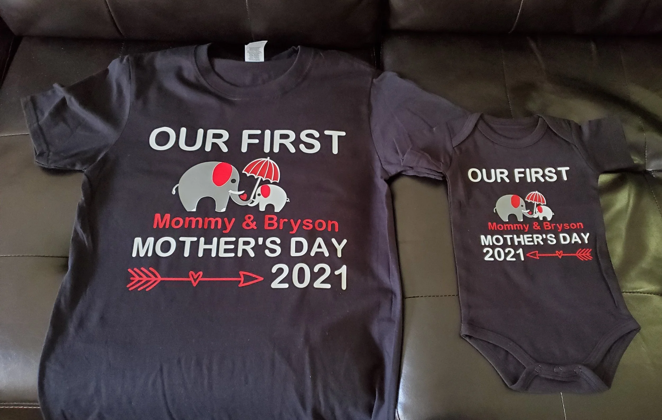 Matching black T-shirt and baby onesie with a design for Mother's Day 2021, featuring elephants under an umbrella, with the text 'Our First Mommy & Bryson Mother's Day 2021' and an arrow graphic.