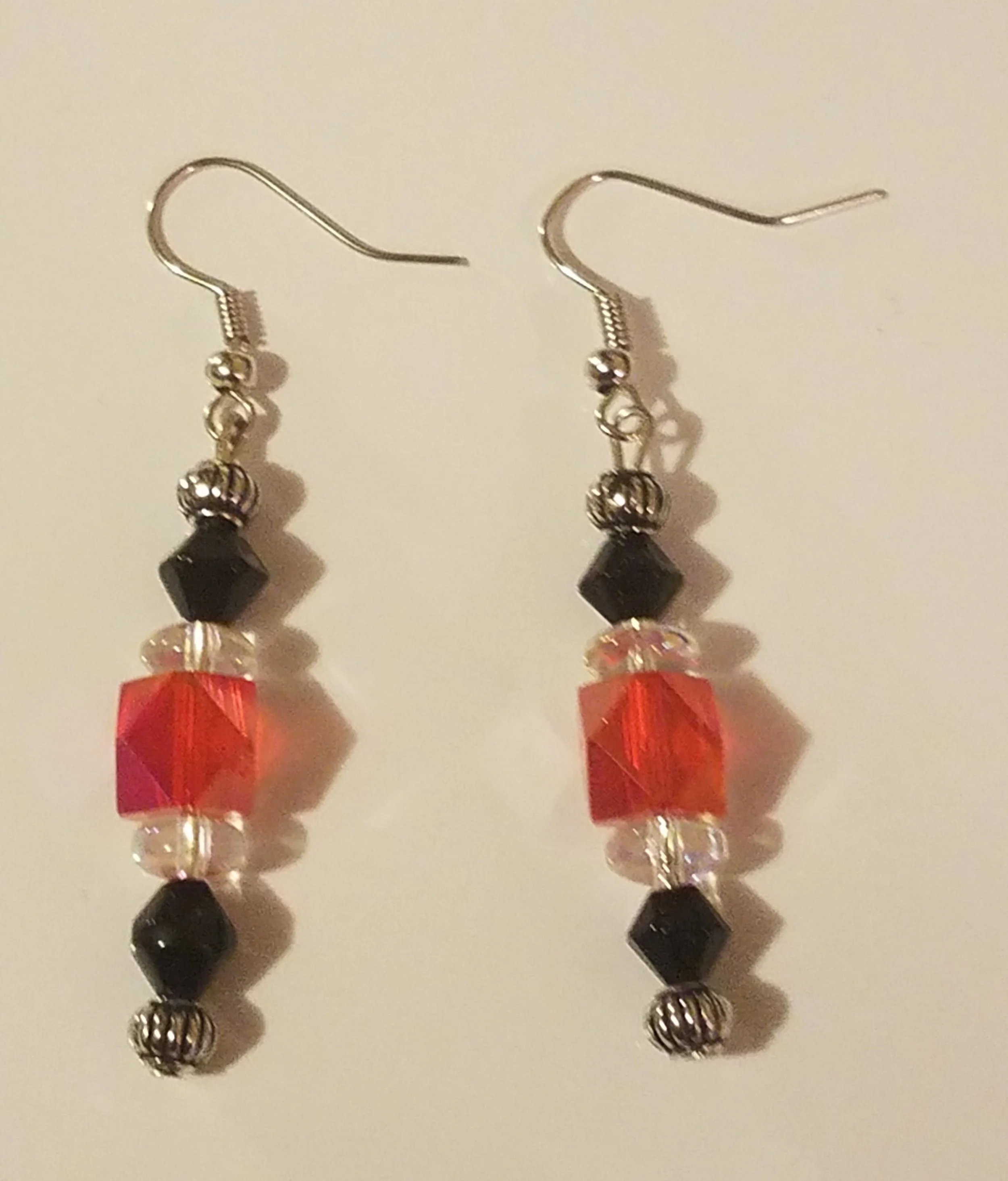Colorful beaded dangle earrings with black, red, and clear beads on silver hooks.