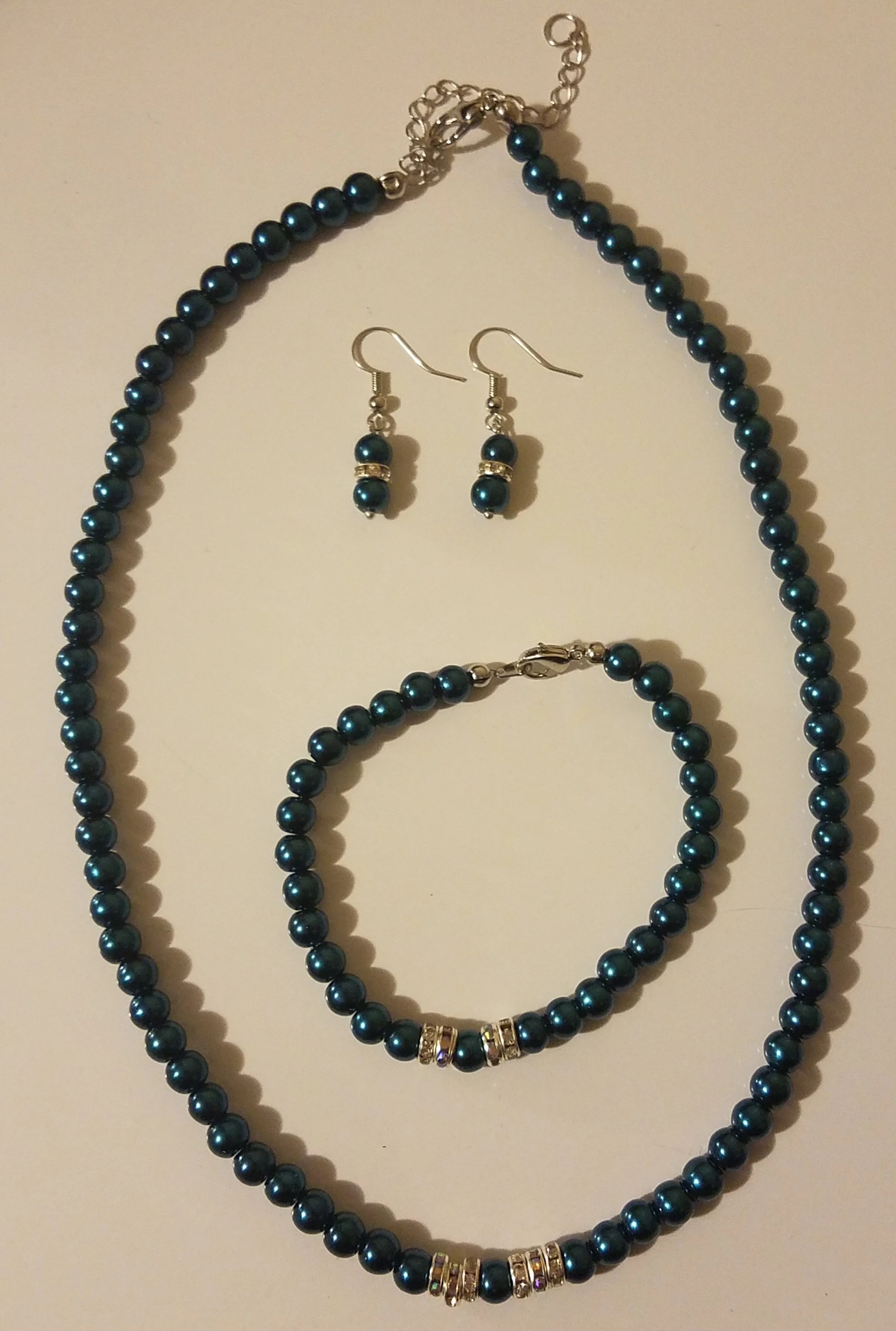 Turquoise pearl jewelry set including a necklace, bracelet, and matching earrings with silver and rhinestone accents.